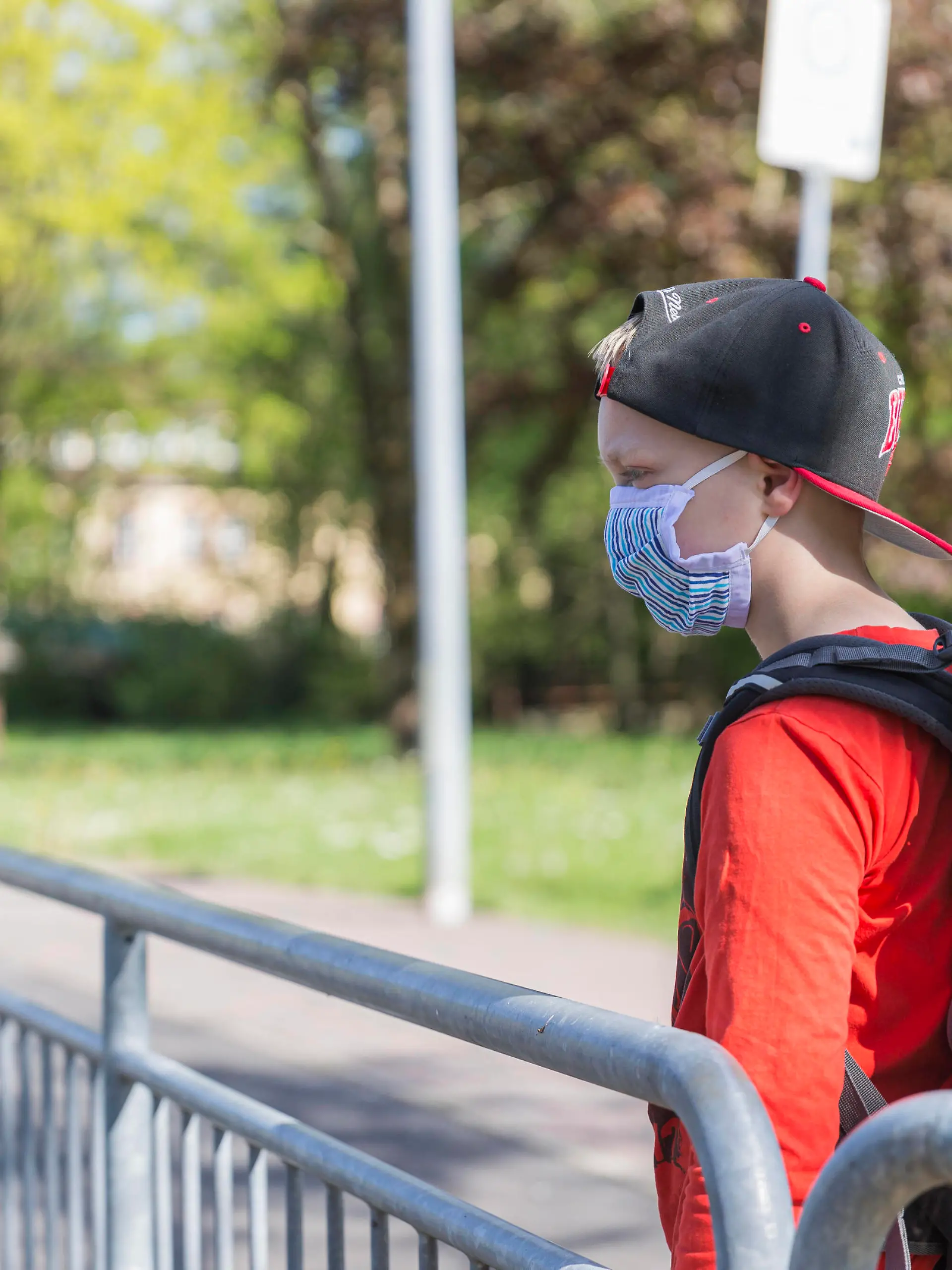  06.05.2020, Corona-Maßnahmen - Maskenpflicht und Schule Ein Junge mit einer Mund-Nasen-Behelfs-Maske und Schulranzen steht an einer Bushaltestelle. Bad Brückenau Bayern Deutschland *** 06 05 2020, Corona measures compulsory mask and school A boy with a mouth nose makeshift mask and school bag is standing at a bus stop Bad Brückenau Bavaria Germany