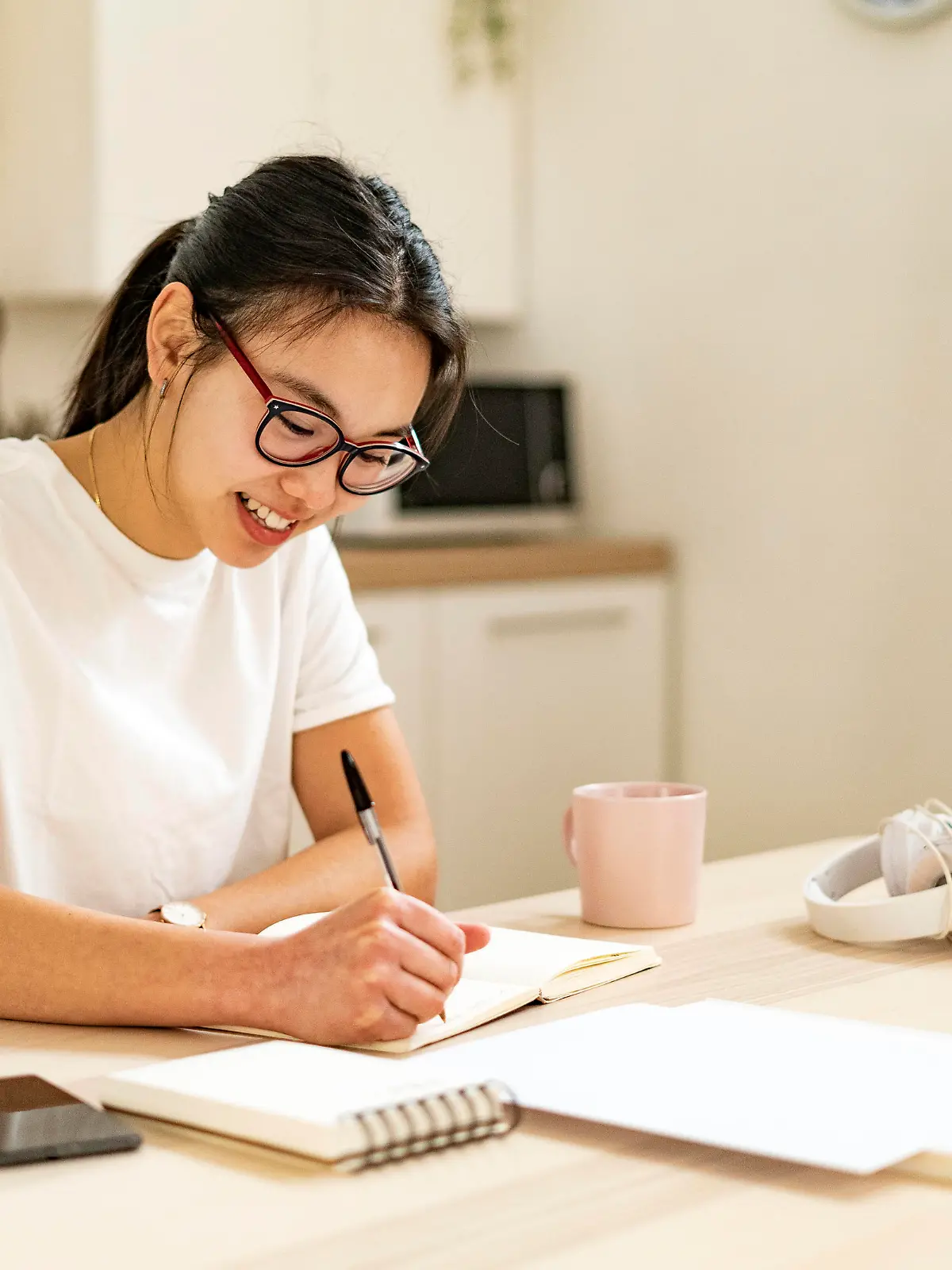 IMAGO Creative: Bildung, Schreiben Smiling woman writing in book at home model released Symbolfoto property released GIOF11677