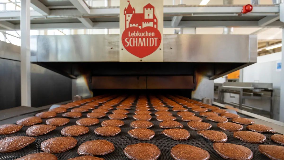 Frisch gebackene Lebkuchen laufen auf einem Band aus einem Ofen in der Produktion des Lebkuchenherstellers Schmidt. Bis zu drei Millionen Lebkuchen laufen in der Hochsaison beim Marktführer Lebkuchen-Schmidt täglich aus dem Ofen. Zutaten abwiegen und die Masse anrühren läuft im großen Maßstab noch von Hand, die Oblaten bestreichen und backen läuft maschinell. Nürnberger Lebkuchen und Aachener Printen haben lange Tradition, experimentieren aber auch gerne mit neuen Trends. Das soll auch den Verkauf ankurbeln außerhalb der Hauptsaison.