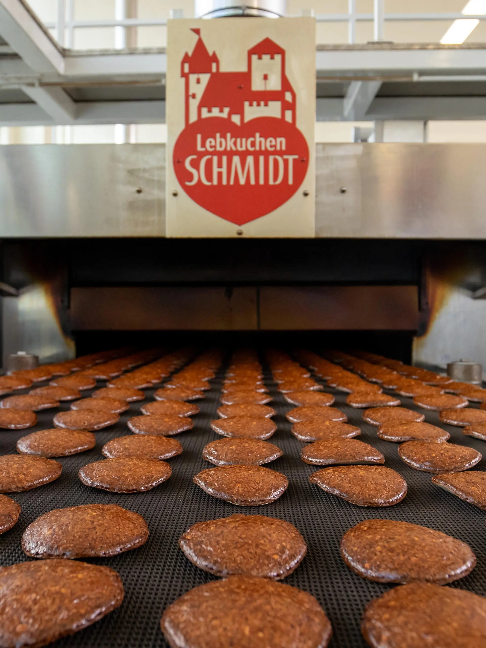 Frisch gebackene Lebkuchen laufen auf einem Band aus einem Ofen in der Produktion des Lebkuchenherstellers Schmidt. Bis zu drei Millionen Lebkuchen laufen in der Hochsaison beim Marktführer Lebkuchen-Schmidt täglich aus dem Ofen. Zutaten abwiegen und die Masse anrühren läuft im großen Maßstab noch von Hand, die Oblaten bestreichen und backen läuft maschinell. Nürnberger Lebkuchen und Aachener Printen haben lange Tradition, experimentieren aber auch gerne mit neuen Trends. Das soll auch den Verkauf ankurbeln außerhalb der Hauptsaison.