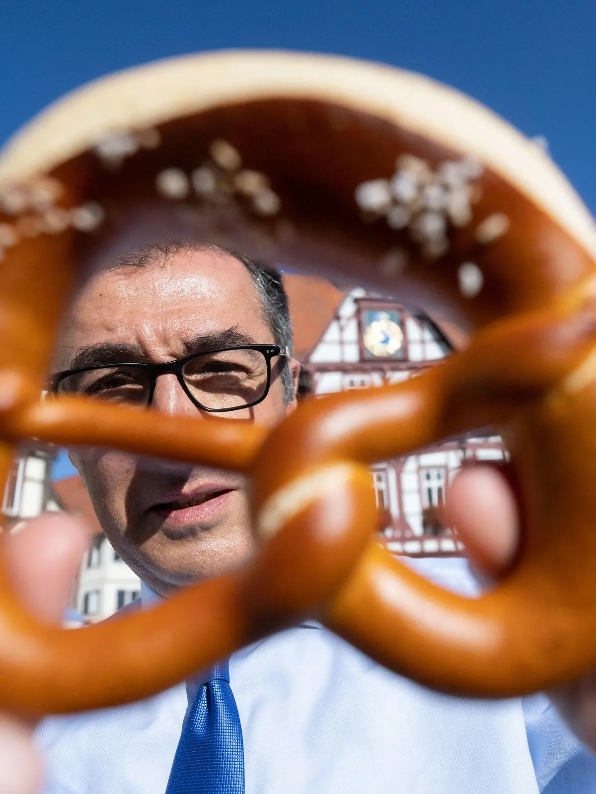 dpatopbilder - 25.08.2022, Baden-Württemberg, Bad Urach: Bundesernährungsminister Cem Özdemir (Bündnis 90/Die Grünen) zeigt auf dem Marktplatz seines Geburtsorts nach dem Besuch einer Bäckerei eine Brezel. Foto: Marijan Murat/dpa +++ dpa-Bildfunk +++