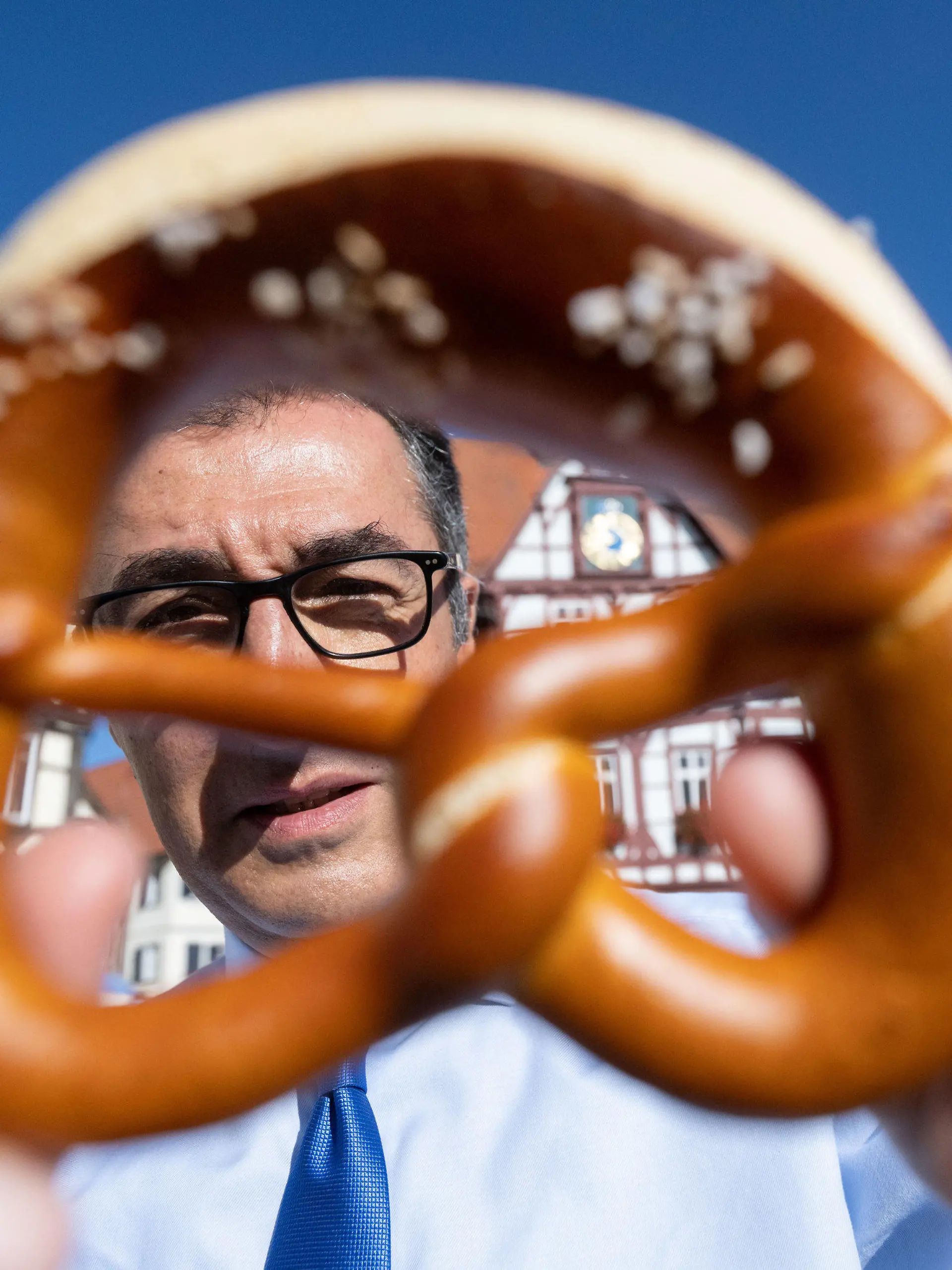 dpatopbilder - 25.08.2022, Baden-Württemberg, Bad Urach: Bundesernährungsminister Cem Özdemir (Bündnis 90/Die Grünen) zeigt auf dem Marktplatz seines Geburtsorts nach dem Besuch einer Bäckerei eine Brezel. Foto: Marijan Murat/dpa +++ dpa-Bildfunk +++