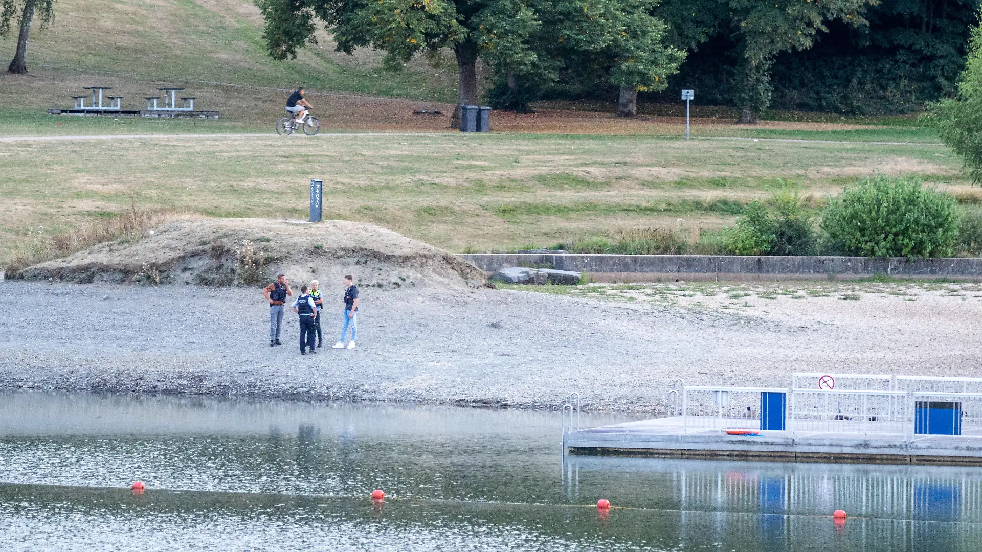 25.08.2022, Nordrhein-Westfalen, Simmerath: Polizisten stehen am Ufer des Eiserbachsees im Rurseezentrum. Nach einem Badeunfall in dem Badesee bei Aachen sind zwei Kinder gestorben. Das teilte eine Sprecherin der Polizei am 26.08. mit. Die sieben und neun Jahre alten Jungen waren laut Polizei am frühen Donnerstagabend am Eiserbachsee als vermisst gemeldet und dann wenig später leblos im Wasser gefunden worden. Foto: Ralf Roeger/dpa +++ dpa-Bildfunk +++