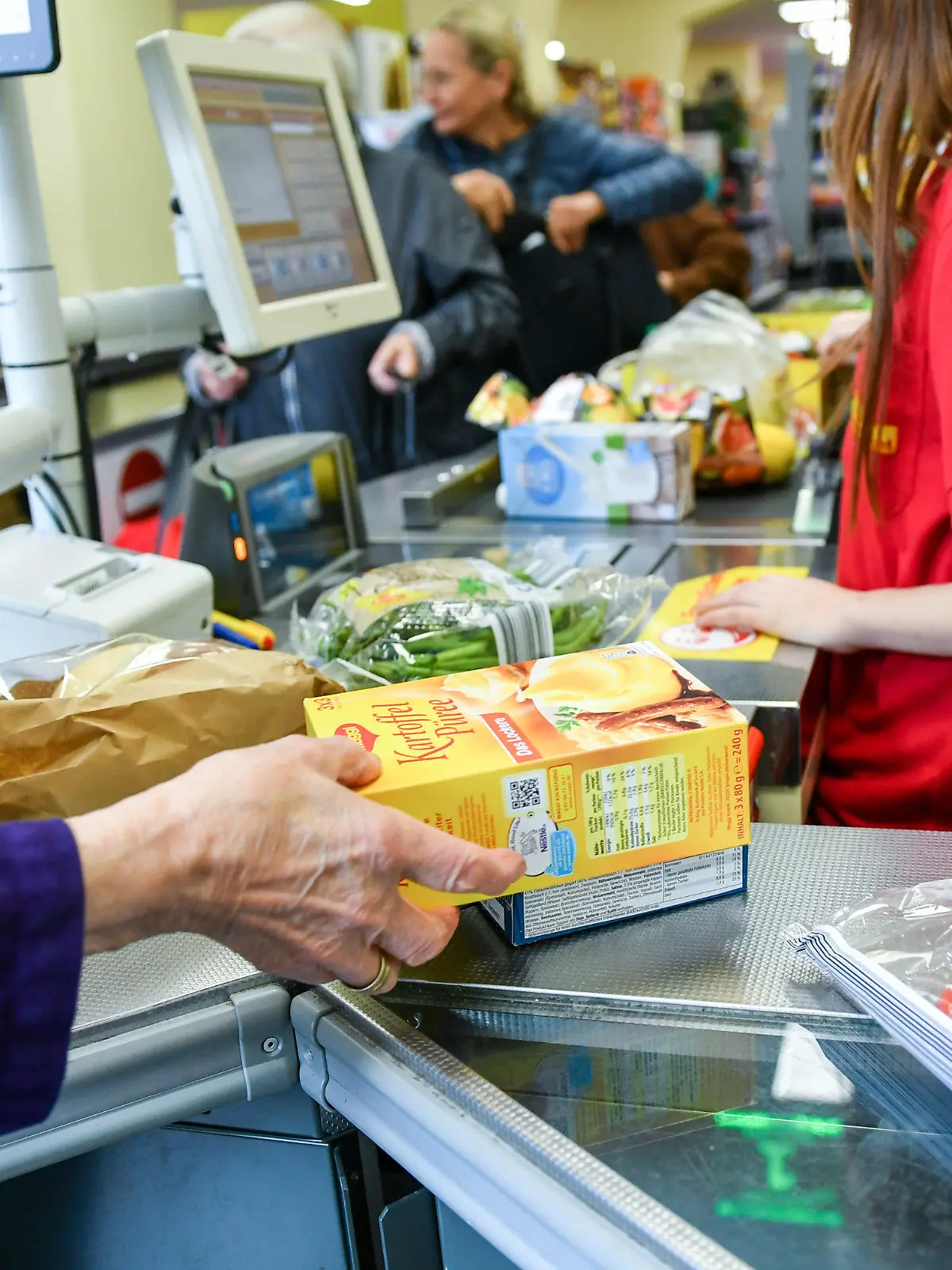 ARCHIV - 18.09.2019, Berlin: Eine Kundin nimmt in einem Supermarkt Waren vom Band an der Kasse, nachdem eine Kassiererin die Waren gescannt hat. Deutsche Verbraucher und Unternehmen müssen sich nach Einschätzung des Ifo-Instituts auf weitere Preiserhöhungen einstellen. (Zu dpa "Ifo: Viele Unternehmen planen Preiserhöhungen") Foto: Jens Kalaene/dpa-Zentralbild/dpa +++ dpa-Bildfunk +++