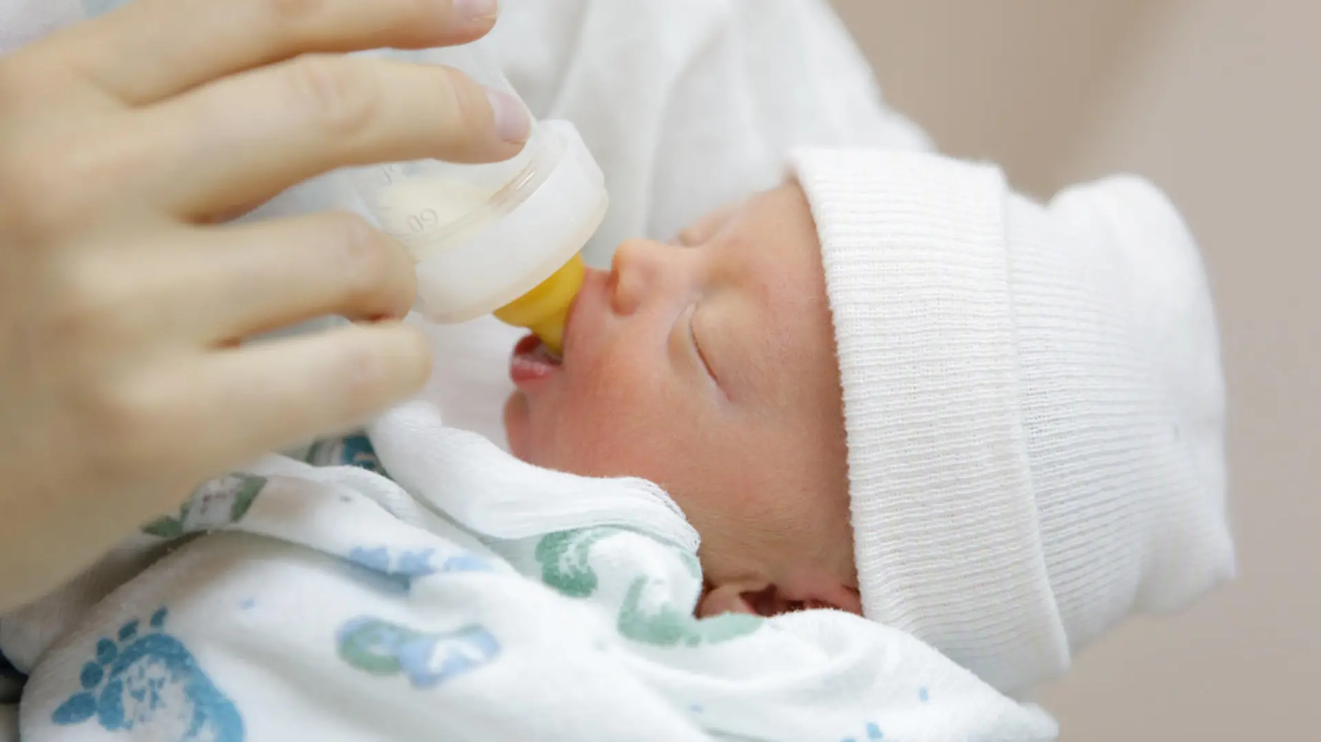 mother bottle feeding her premature baby in the hospital nursery