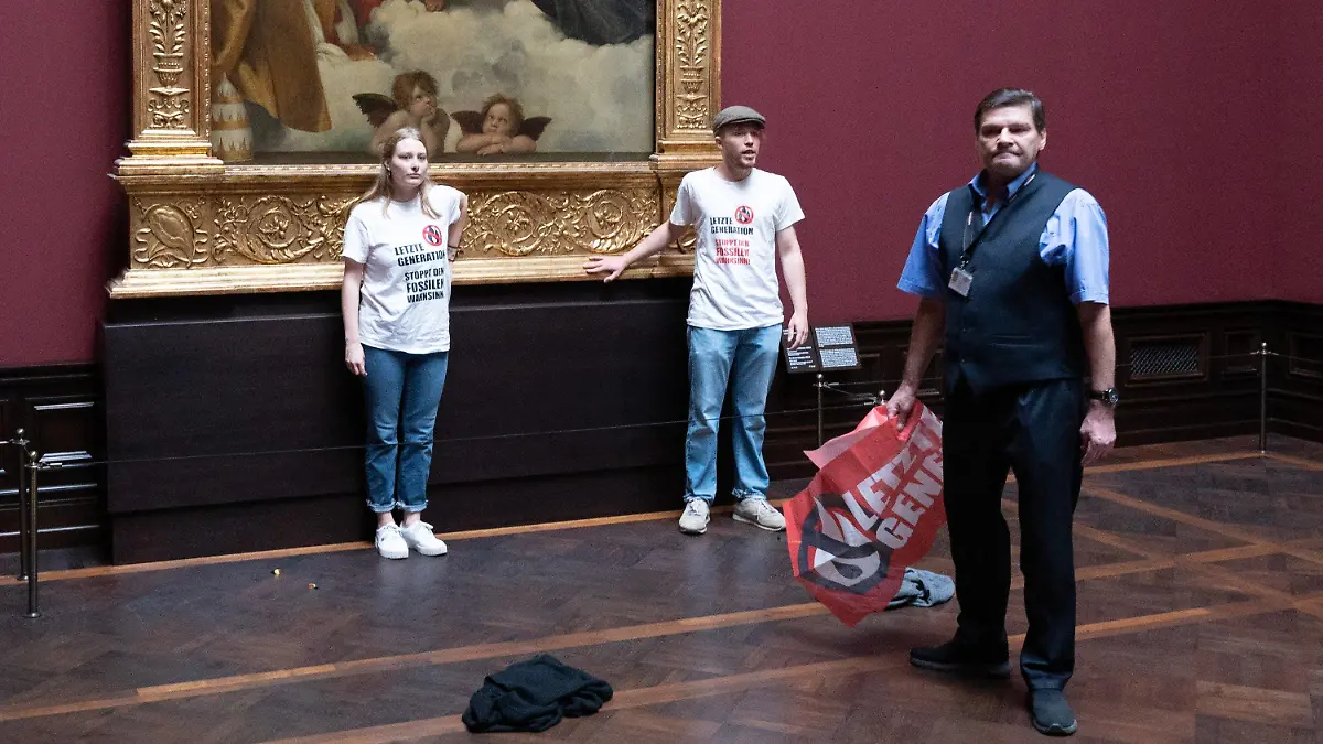 23.08.2022, Sachsen, Dresden: Zwei Umweltaktivisten der Gruppe ·Letzte Generation· stehen in der Gemäldegalerie Alte Meister an dem Gemälde ·Sixtinische Madonna· von Raffael. Foto: Sebastian Kahnert/dpa - ACHTUNG: Nur zur redaktionellen Verwendung im Zusammenhang mit der aktuellen Berichterstattung und nur mit vollständiger Nennung des vorstehenden Credits +++ dpa-Bildfunk +++
