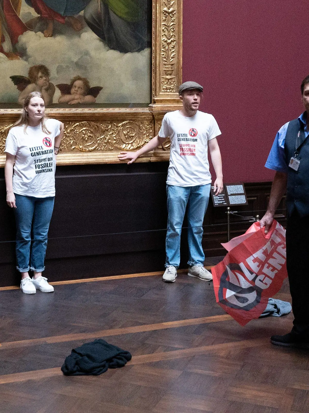 23.08.2022, Sachsen, Dresden: Zwei Umweltaktivisten der Gruppe ·Letzte Generation· stehen in der Gemäldegalerie Alte Meister an dem Gemälde ·Sixtinische Madonna· von Raffael. Foto: Sebastian Kahnert/dpa - ACHTUNG: Nur zur redaktionellen Verwendung im Zusammenhang mit der aktuellen Berichterstattung und nur mit vollständiger Nennung des vorstehenden Credits +++ dpa-Bildfunk +++