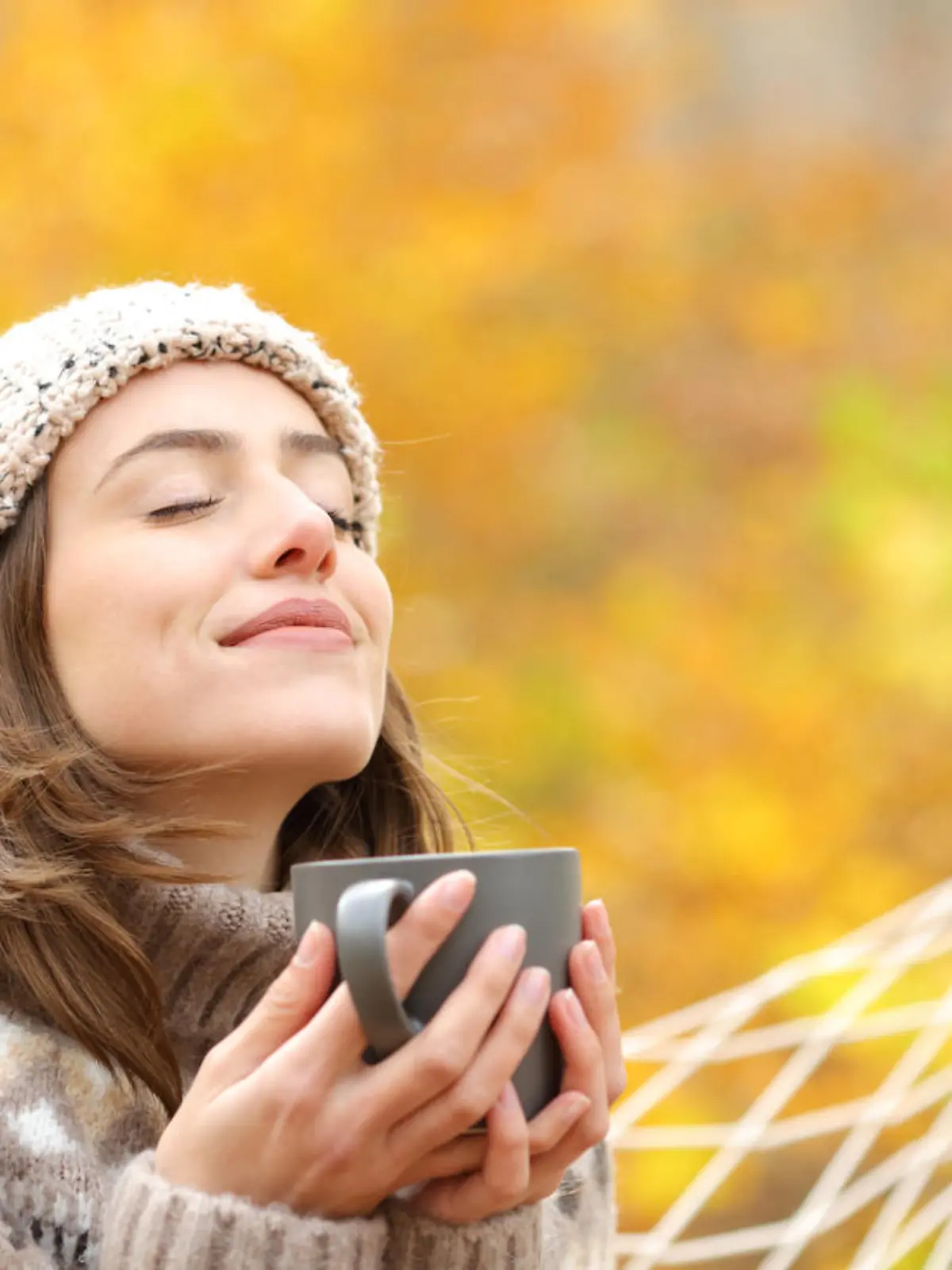 Woman breaths fresh air holding coffee cup in autumn