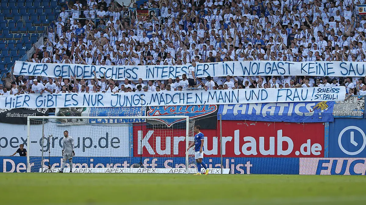 ROSTOCK, GERMANY - AUGUST 21: Supporters of FC Hansa Rostock holding up a sign with a slight jab towards FC St. Pauli and their latest action with the gender asterisk on the last home shirt during the Second Bundesliga match between F.C. Hansa Rostock and FC St. Pauli at Ostseestadion on August 21, 2022 in Rostock, Germany. (Photo by Cathrin Mueller/Getty Images)