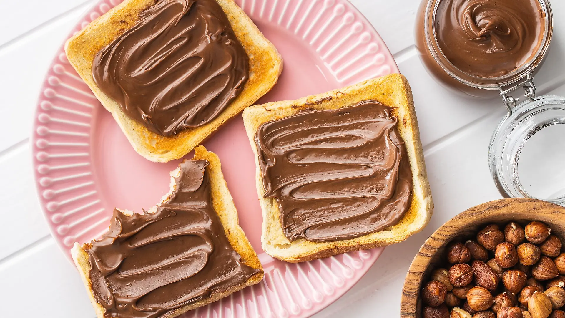 Toast bread with hazelnut spread on pink plate. Sweet chocolate cream. Top view.