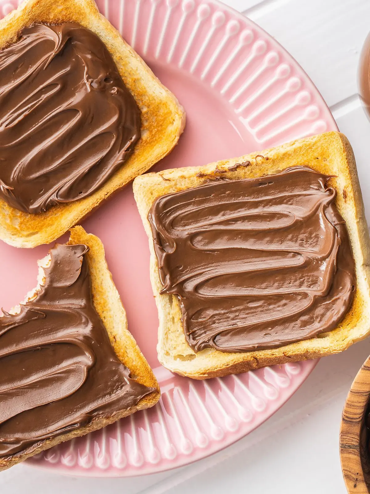 Toast bread with hazelnut spread on pink plate. Sweet chocolate cream. Top view.