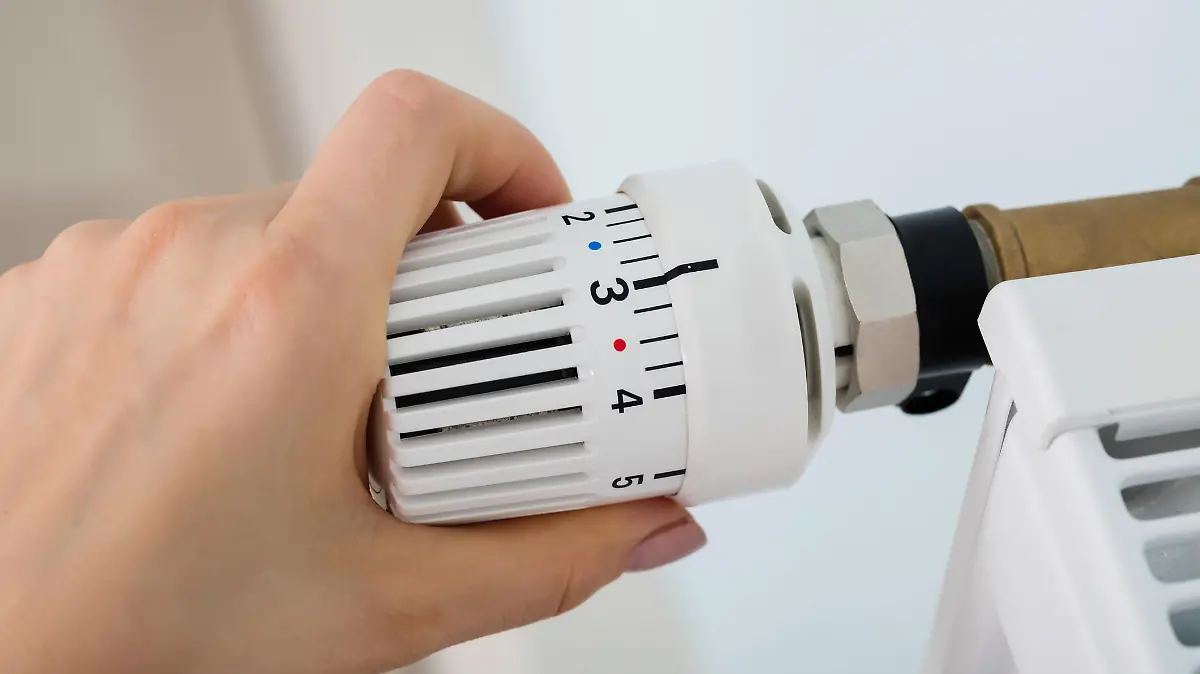 Frau dreht am Thermostat der Heizung