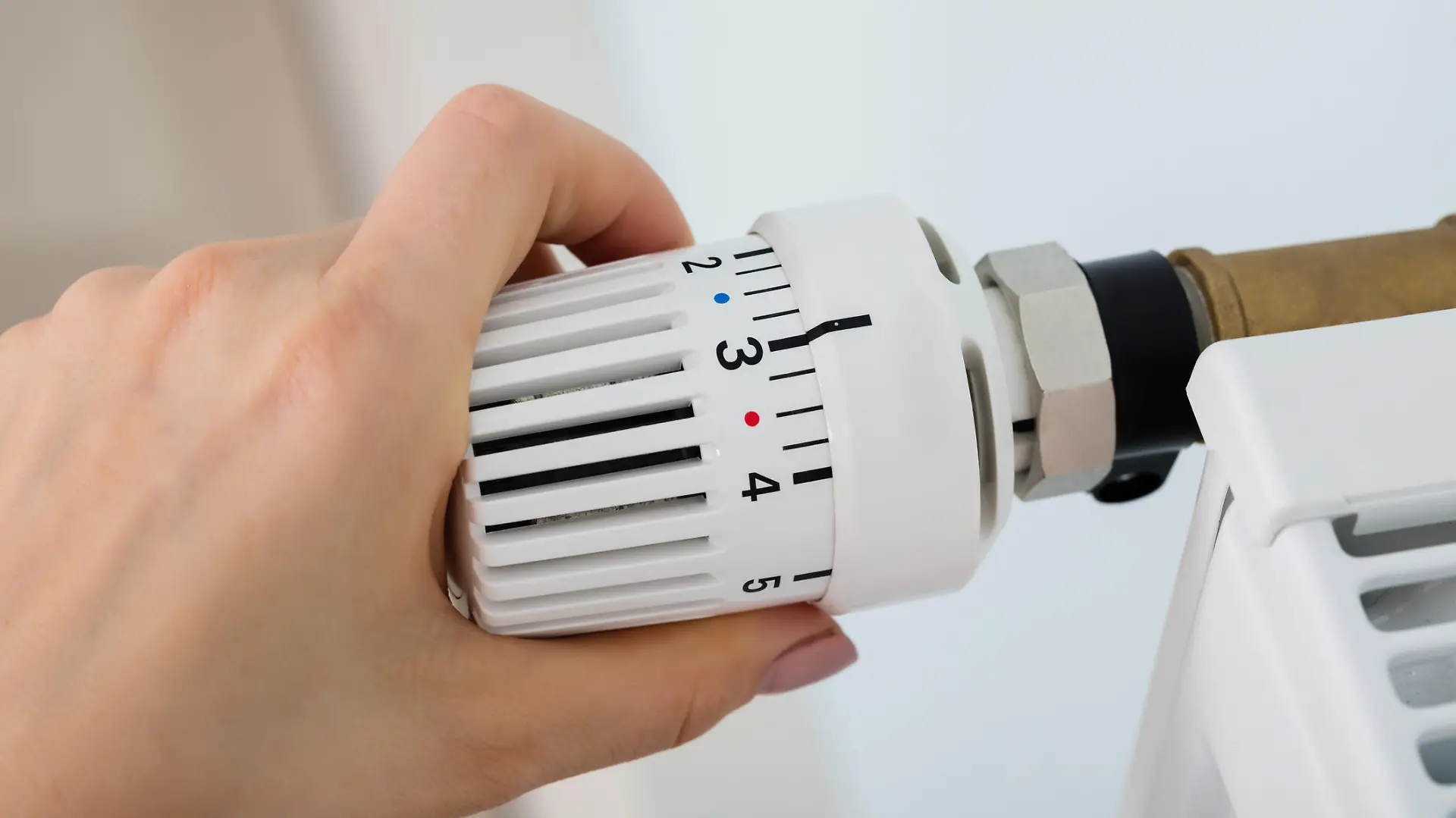 Frau dreht am Thermostat der Heizung