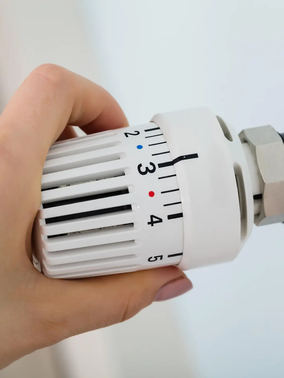 Frau dreht am Thermostat der Heizung