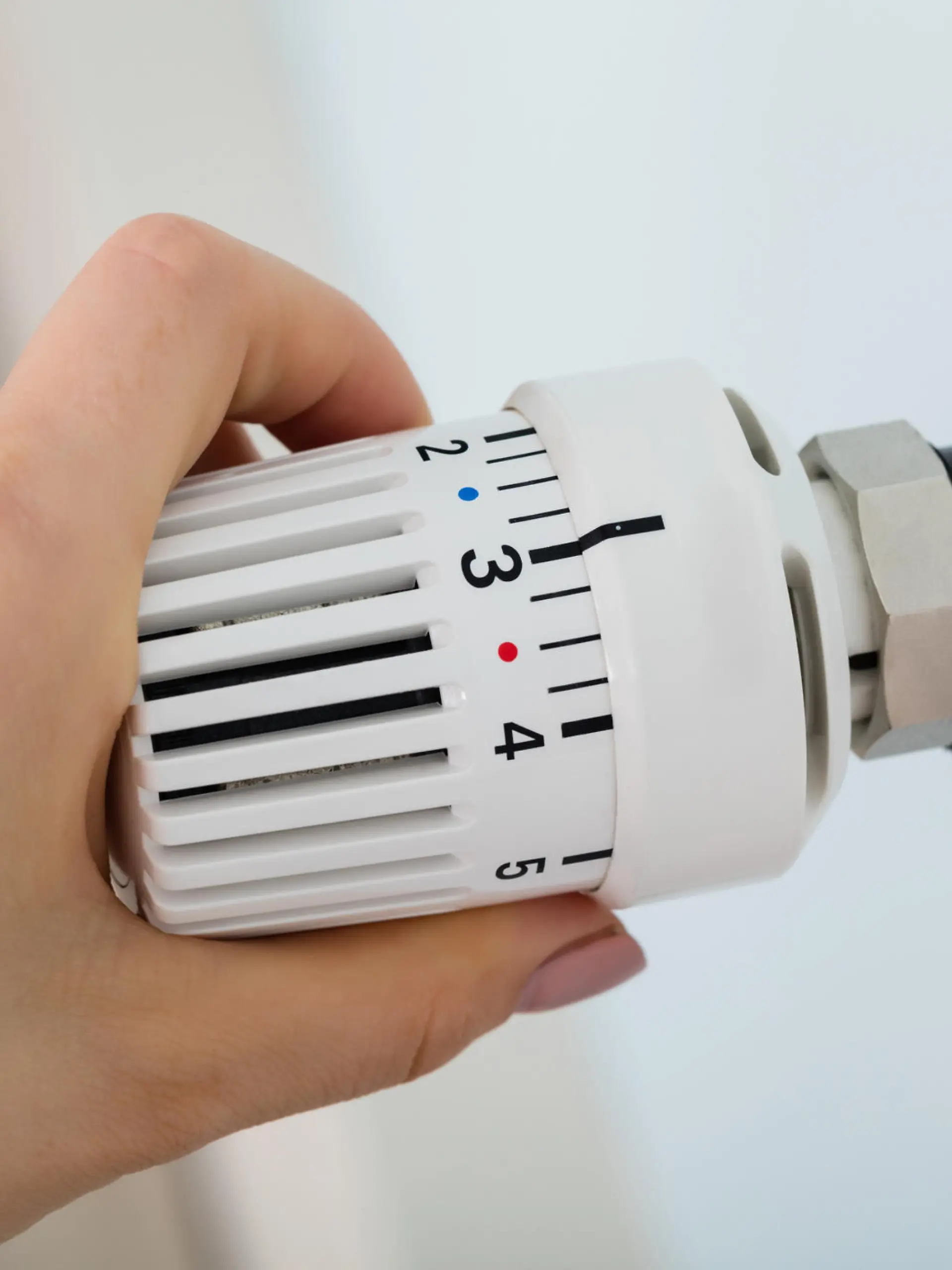 Frau dreht am Thermostat der Heizung