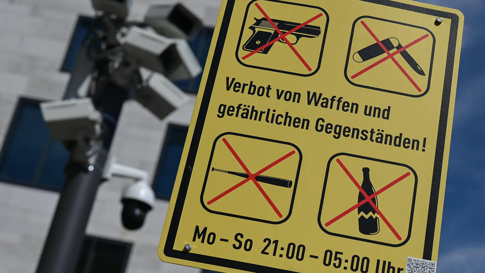 04.08.2022, Hessen, Wiesbaden: Neben Überwachungskameras weist ein Sonderzeichen mit durchgestrichenen Symbolen nahe des Wiesbadener Platz der Deutschen Einheit auf ein Verbot von Waffen und gefährlichen Gegenständen von Montag bis Sonntags von 21 bis 5 Uhr hin. Die Kriminalitätsbelastung geht in Hessen von Jahr zu Jahr zurück. Dennoch klagen weiterhin Bürger gerade in den Städten über «Angsträume», schummerige Orte, an denen sie sich bedroht fühlen. Um für mehr Sicherheit in der Bevölkerung zu sorgen, hatte Wiesbaden Anfang des Jahres 2019 die erste Waffenverbotszone in Hessen geschaffen. (zu dpa "Kassel prüft Einrichtung von Waffenverbotszone") Foto: Arne Dedert/dpa +++ dpa-Bildfunk +++