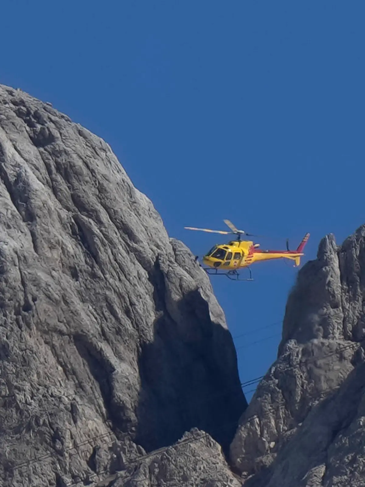 04.07.2022, Italien, Canazei: Ein Rettungshubschrauber überfliegt den Punta-Rocca-Gletscher in der Nähe von Canazei in den italienischen Alpen. Nach dem massiven Gletscherbruch und einer Lawine geht in den Dolomiten die Suche nach weiteren Toten unter erschwerten Bedingungen weiter. Ein siebtes Opfer wurde am 04.07.22 entdeckt, weitere werden befürchtet. Foto: Luca Bruno/AP/dpa +++ dpa-Bildfunk +++
