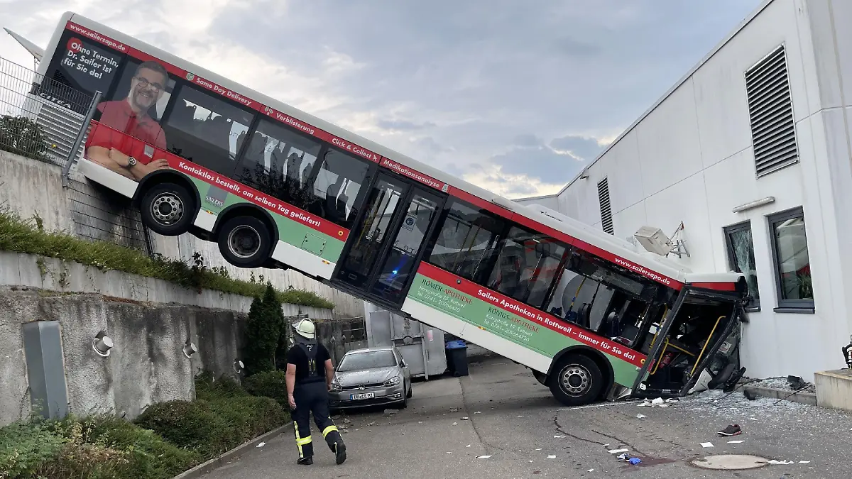 19.08.2022, Baden-Württemberg, Herrenberg: Der hintere Teil eines Busses hängt an einer Mauer, der vordere Teil landete in der Fassade eines Discounters. Der 72-jährige Fahrer dieses Busses ist nach dem Unfall schwer verletzt mit einem Hubschrauber ins Krankenhaus gebracht worden. Foto: Sdmg / Schulz/SDMG/dpa +++ dpa-Bildfunk +++