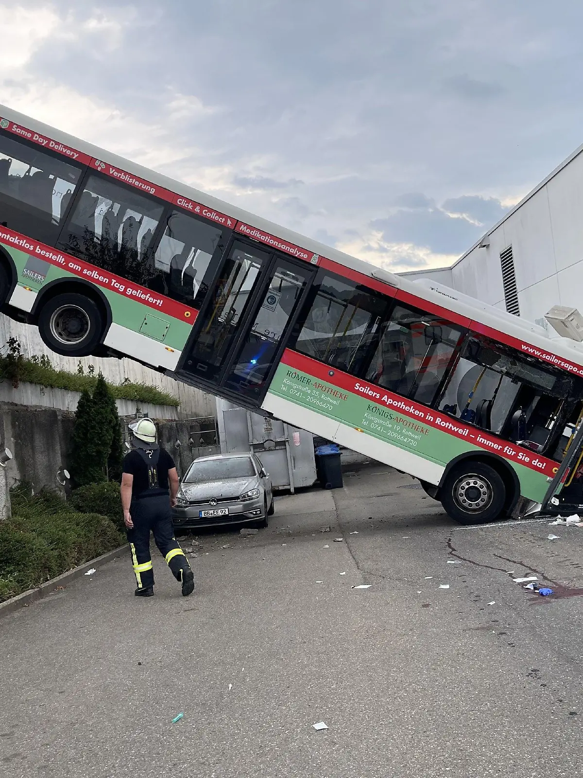19.08.2022, Baden-Württemberg, Herrenberg: Der hintere Teil eines Busses hängt an einer Mauer, der vordere Teil landete in der Fassade eines Discounters. Der 72-jährige Fahrer dieses Busses ist nach dem Unfall schwer verletzt mit einem Hubschrauber ins Krankenhaus gebracht worden. Foto: Sdmg / Schulz/SDMG/dpa +++ dpa-Bildfunk +++