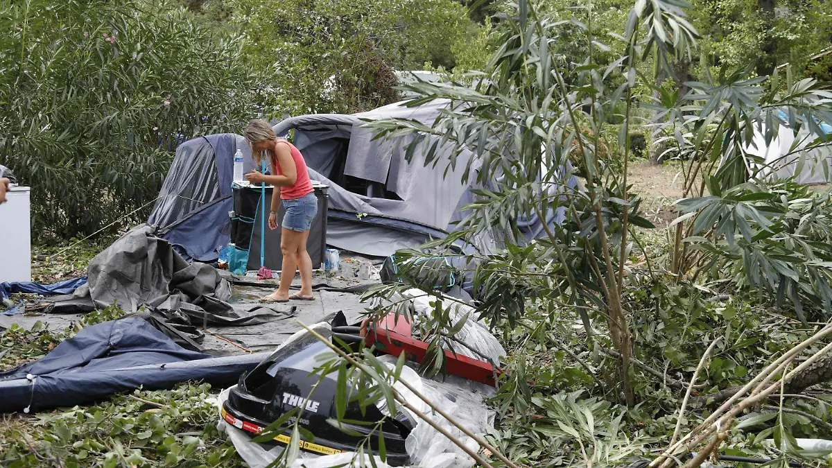 dpatopbilder - 18.08.2022, Frankreich, Coggia: Eine Frau packt die Reste der zerstörten Zelte und anderen Gegenstände auf dem Campingplatz Sagone ein, wo ein Baum während eines Sturms auf einen Bungalow stürzte und eine Person tötete. Bei heftigen Unwettern auf der französischen Mittelmeerinsel Korsika sind mehrere Menschen gestorben. Foto: Pascal Pochard-Casabianca/AFP/dpa +++ dpa-Bildfunk +++