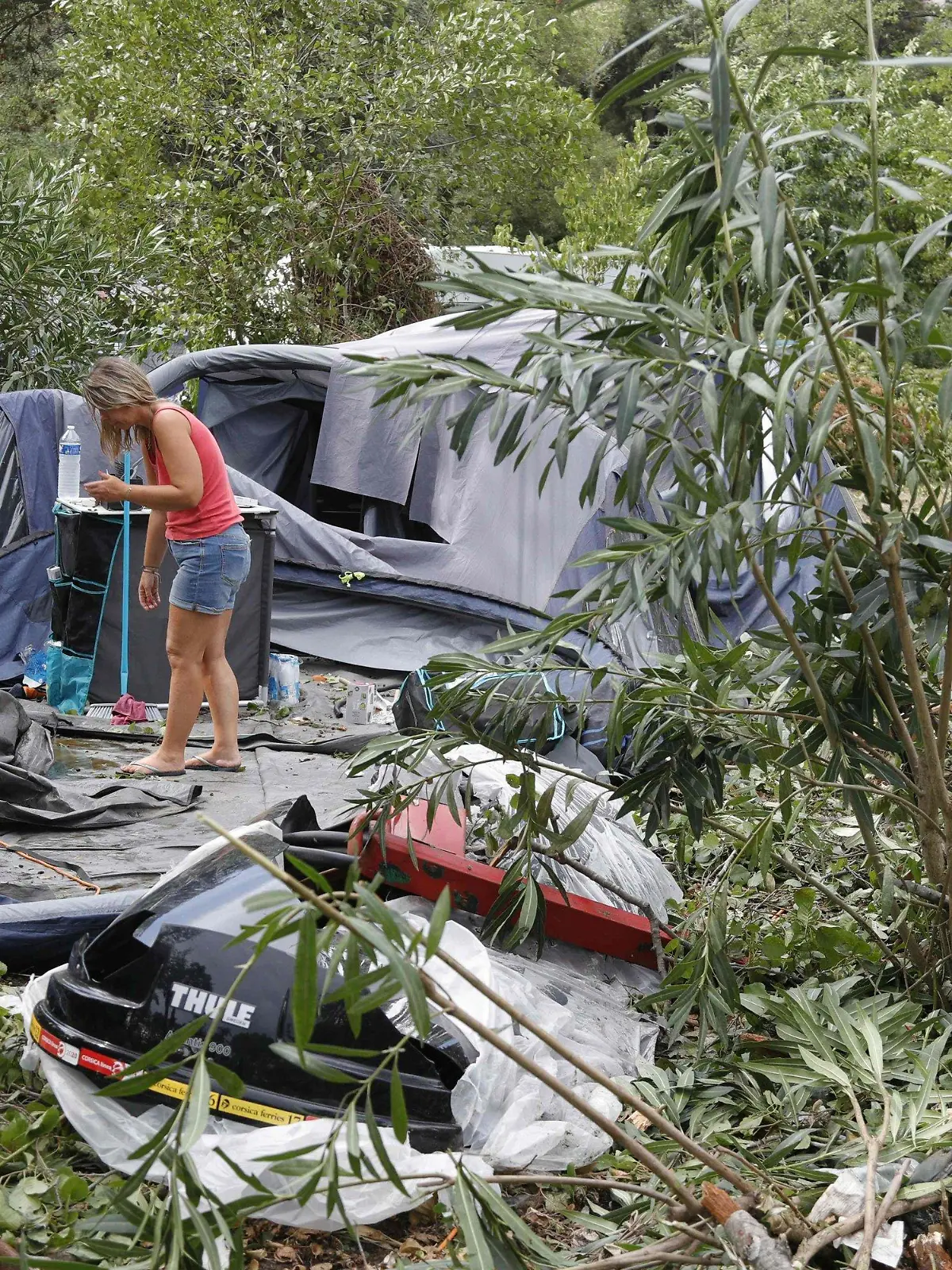 dpatopbilder - 18.08.2022, Frankreich, Coggia: Eine Frau packt die Reste der zerstörten Zelte und anderen Gegenstände auf dem Campingplatz Sagone ein, wo ein Baum während eines Sturms auf einen Bungalow stürzte und eine Person tötete. Bei heftigen Unwettern auf der französischen Mittelmeerinsel Korsika sind mehrere Menschen gestorben. Foto: Pascal Pochard-Casabianca/AFP/dpa +++ dpa-Bildfunk +++