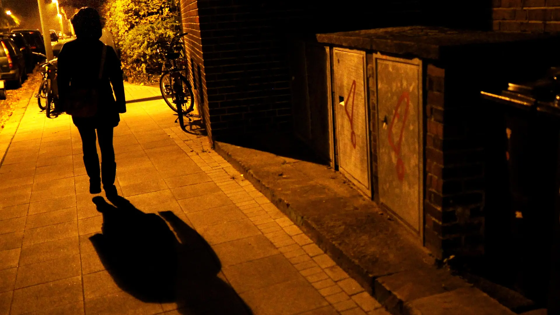 Eine Frau geht am 23.10.2012 im Licht der Straßenlaternen über eine Straße in Hannover und wirft einen langen Schatten. Foto: Julian Stratenschulte/dpa