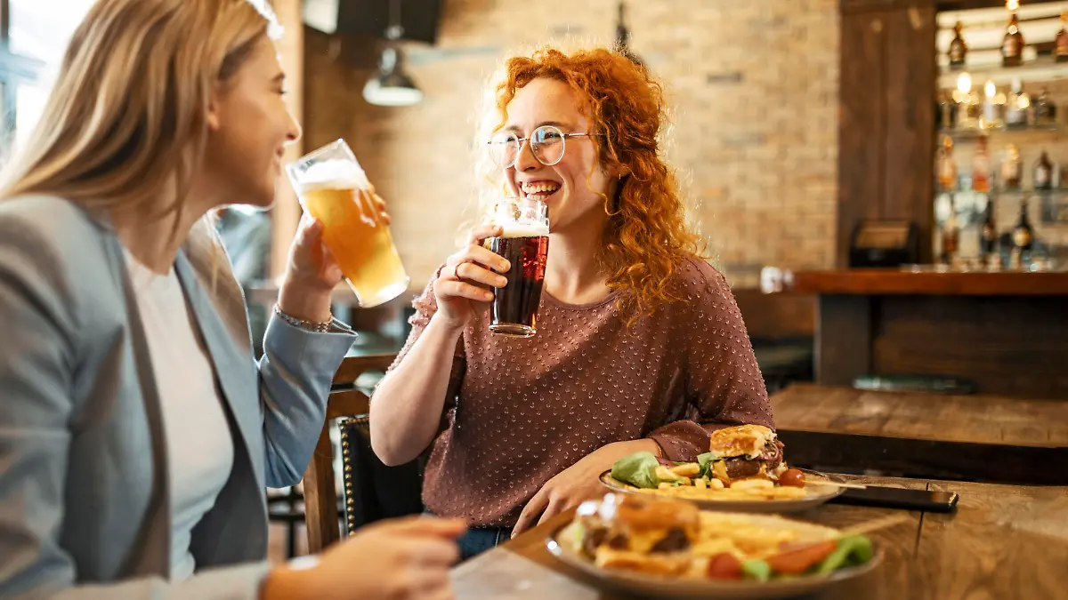 Happy Female Friends Having meal And Beer And Laughing