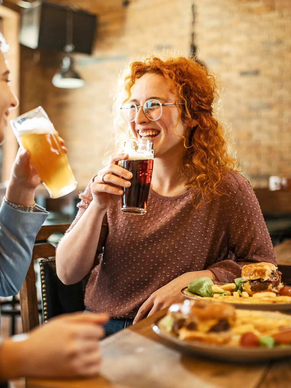 Happy Female Friends Having meal And Beer And Laughing
