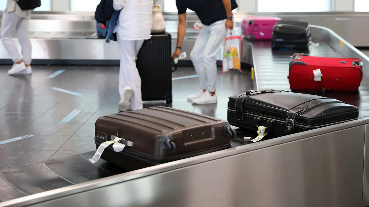 Reisende warten nach der Landung auf ihre Koffer am Gepäckband.
