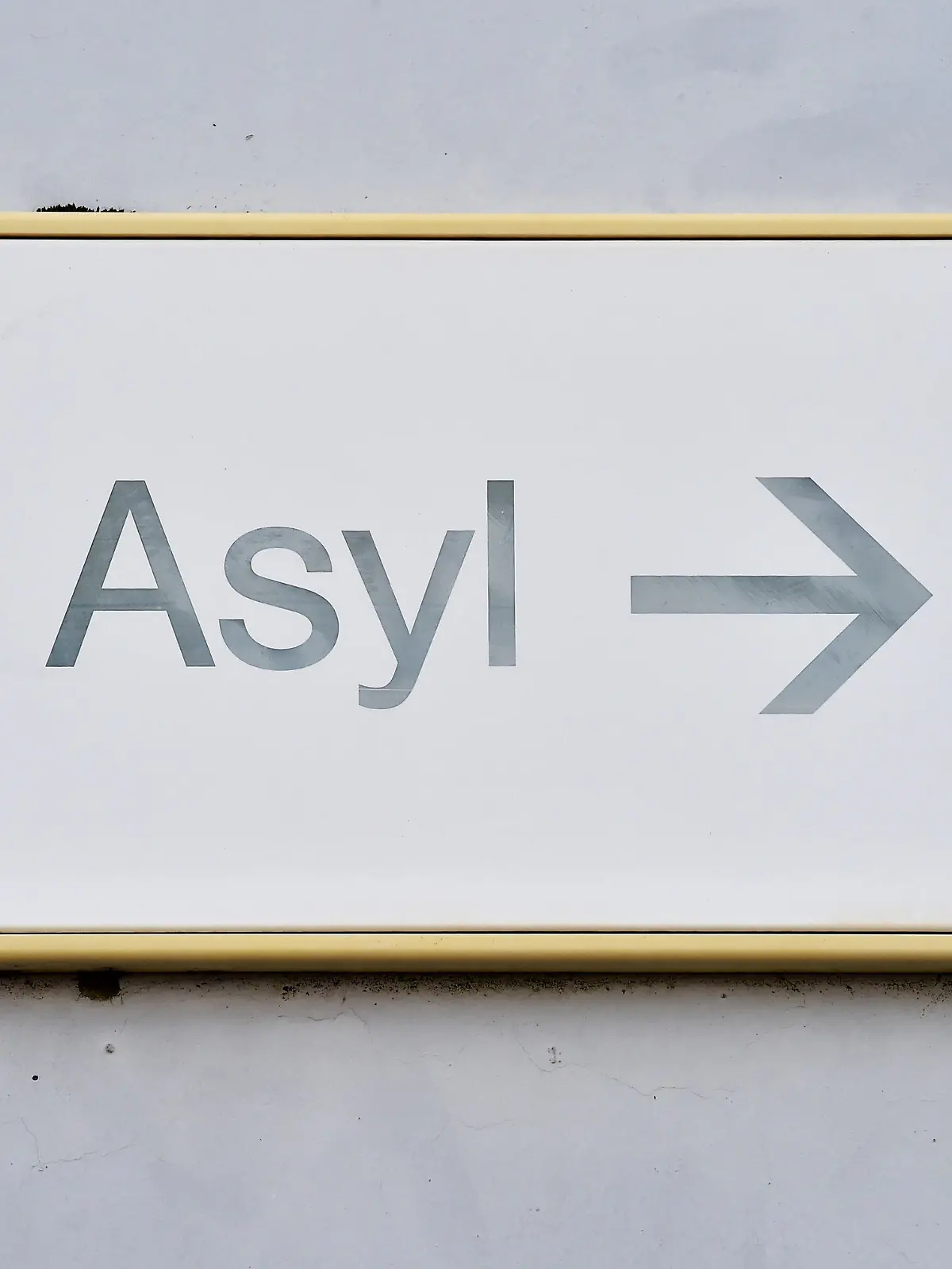 ARCHIV - 04.08.2014, Baden-Württemberg, Karlsruhe: Ein Schild mit der Aufschrift «Asyl» hängt in der Landeserstaufnahme für Asylbewerber (LEA) an einer Wand. Nach der scharfen Kritik an den Aussagen von Baden-Württembergs Ministerpräsident Winfried Kretschmann zum sogenannten Asylkompromiss erhält der Regierungschef parteiübergreifend Rückendeckung aus seinem Kabinett. (zu dpa: «Kretschmann bekommt Unterstützung im Streit um Asylkompromiss») Foto: Uli Deck/dpa +++ dpa-Bildfunk +++