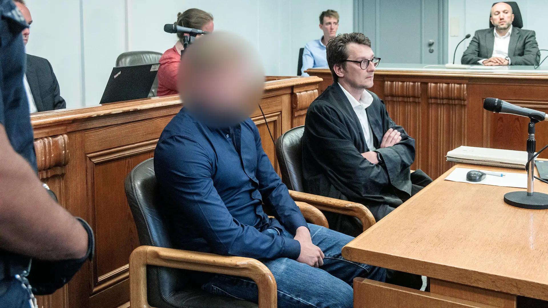 18.08.2022, Schleswig-Holstein, Kiel: Der Angeklagte (Ml), ein 26-jähriger Mann, sitzt neben seinem Anwalt Martin Schaar (Mr) in einem Gerichtssaal des Kieler Landgerichts. Er soll im Januar 2021 unter Einfluss von Drogen und ohne Fahrerlaubnis mit einem Auto bei überhöhter Geschwindigkeit in einer langgezogenen Rechtskurve von der Fahrbahn abgekommen sein und eine Fußgängergruppe auf dem Gehweg erfasst haben. Dabei starben drei Menschen. Foto: Markus Scholz/dpa +++ dpa-Bildfunk +++