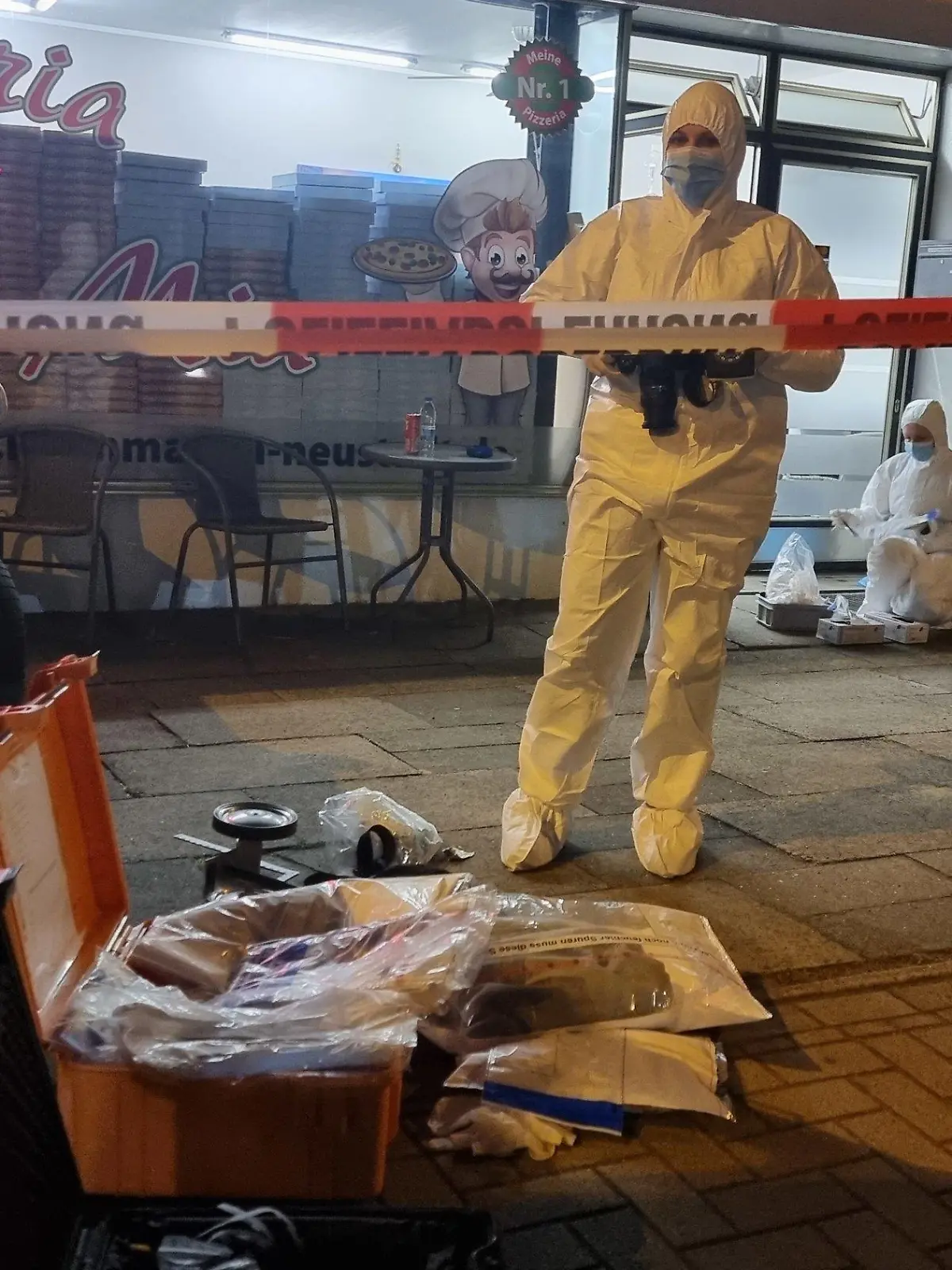 19.08.2022, Niedersachsen, Neustadt am Rübenberge: Polizeibeamte bei der Spurnesicherung. Bei einer Messerstecherei vor einer Pizzeria in Neustadt am Rübenberge ist ein Mann ums Leben gekommen. Er habe sich bei dem Angriff auf offener Straße noch in das Lokal retten können, sei dort jedoch verstorben, wie ein Sprecher der Polizeidirektion Hannover sagte. Eine Frau sei bei der Attacke am Freitagabend verletzt worden, sie wurde demnach in ein Krankenhaus gebracht. Der Täter sei noch vor Ort von den Einsatzkräften überwältigt und festgenommen worden. Foto: -/TNN/dpa - ACHTUNG: KFZ Kennzeichen wurde(n) aus rechtlichen Gründen gepixelt +++ dpa-Bildfunk +++
