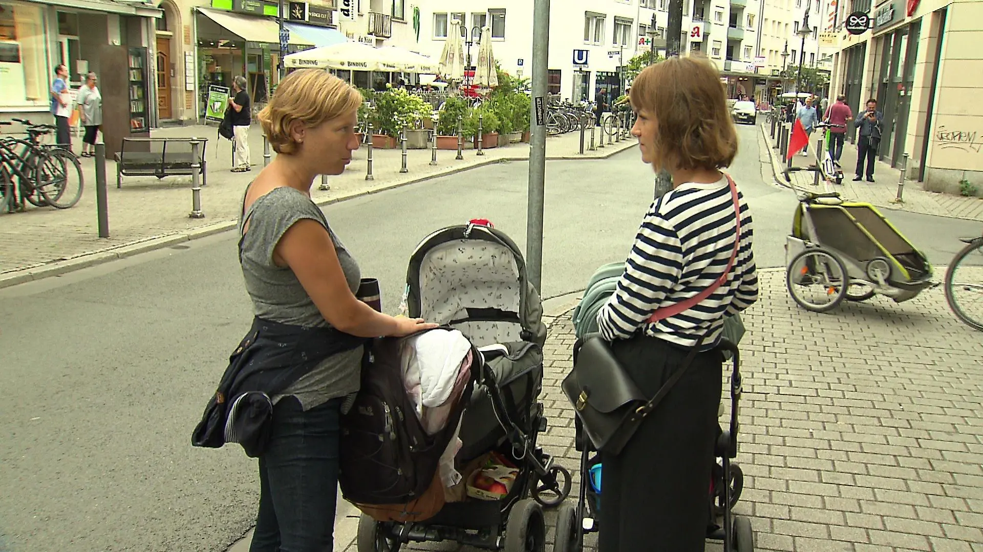 Zwei Mütter mit Kinderwägen auf der Straße.