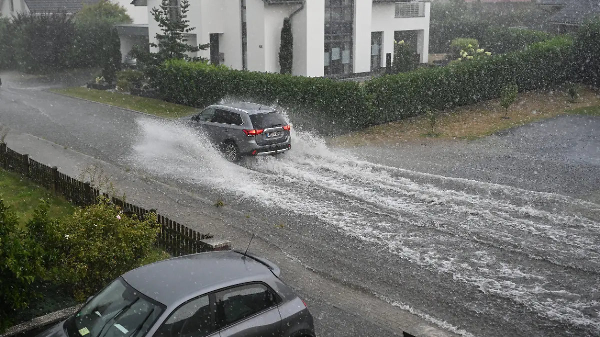 15.08.2022, Niedersachsen, Leer: Ein Auto fährt auf einer überfluteten Straße. Foto: Lars Klemmer/dpa +++ dpa-Bildfunk +++