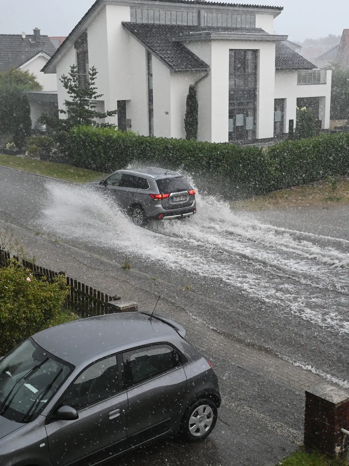 15.08.2022, Niedersachsen, Leer: Ein Auto fährt auf einer überfluteten Straße. Foto: Lars Klemmer/dpa +++ dpa-Bildfunk +++