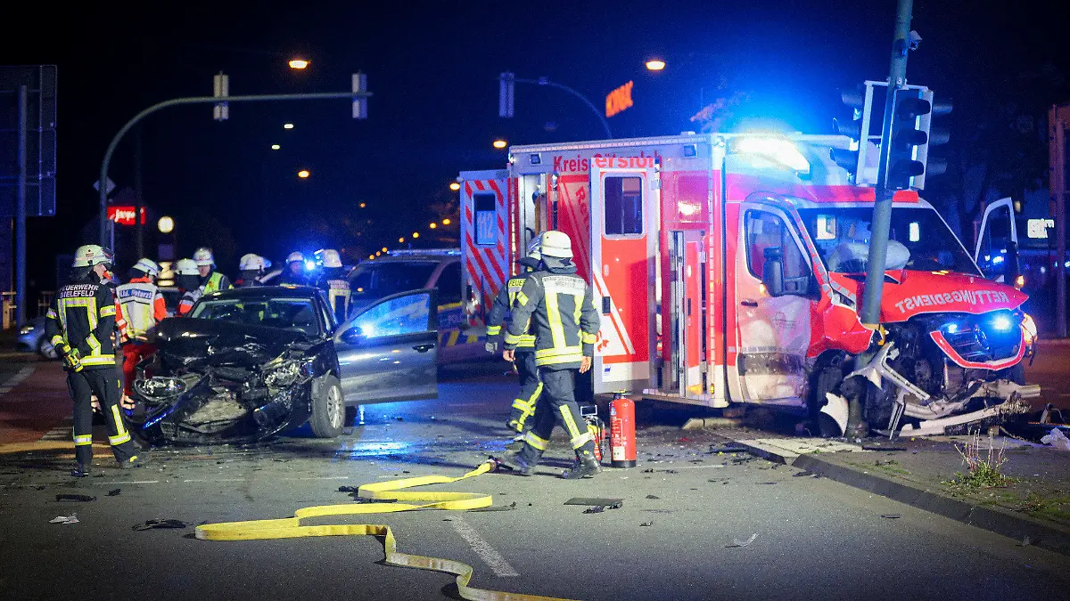 18.04.2024, Nordrhein-Westfalen, Bielefeld: Zwei verunfallte Fahrzeuge stehen auf einer Kreuzung. Nach einem Unfall zwischen einem Krankenwagen und einem Auto in Bielefeld schwebt ersten Erkenntnissen zufolge mindestens ein Mensch in Lebensgefahr. Vier weitere Menschen seien zum Teil schwer verletzt worden, teilte die Polizei am späten Donnerstagabend mit. Foto: Christian Müller/Westfalennews/dpa +++ dpa-Bildfunk +++
