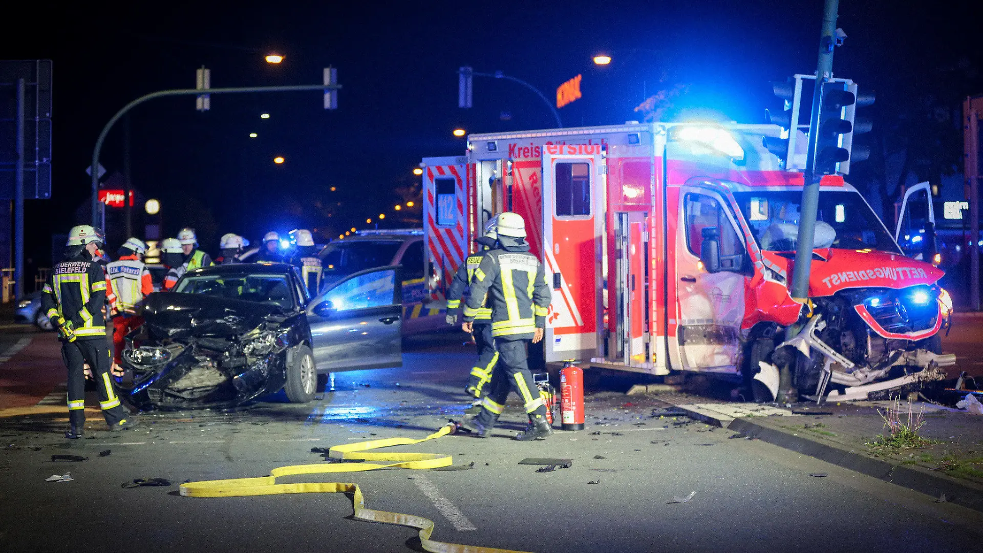 18.04.2024, Nordrhein-Westfalen, Bielefeld: Zwei verunfallte Fahrzeuge stehen auf einer Kreuzung. Nach einem Unfall zwischen einem Krankenwagen und einem Auto in Bielefeld schwebt ersten Erkenntnissen zufolge mindestens ein Mensch in Lebensgefahr. Vier weitere Menschen seien zum Teil schwer verletzt worden, teilte die Polizei am späten Donnerstagabend mit. Foto: Christian Müller/Westfalennews/dpa +++ dpa-Bildfunk +++