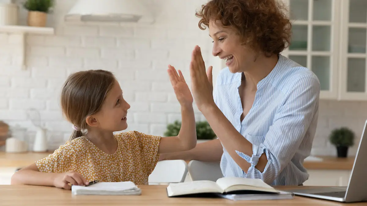 Well done dear. Excited mother give high five to small daughter praise child for reaching success in homework. Joyful female tutor greet schoolgirl for giving correct answer solving hard math problem