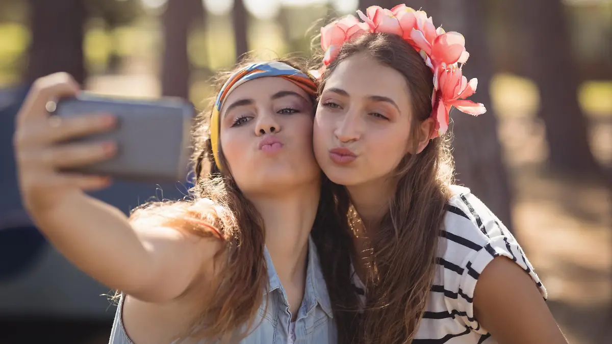 Close up of women puckering while clicking selfie in forest || Modellfreigabe vorhanden