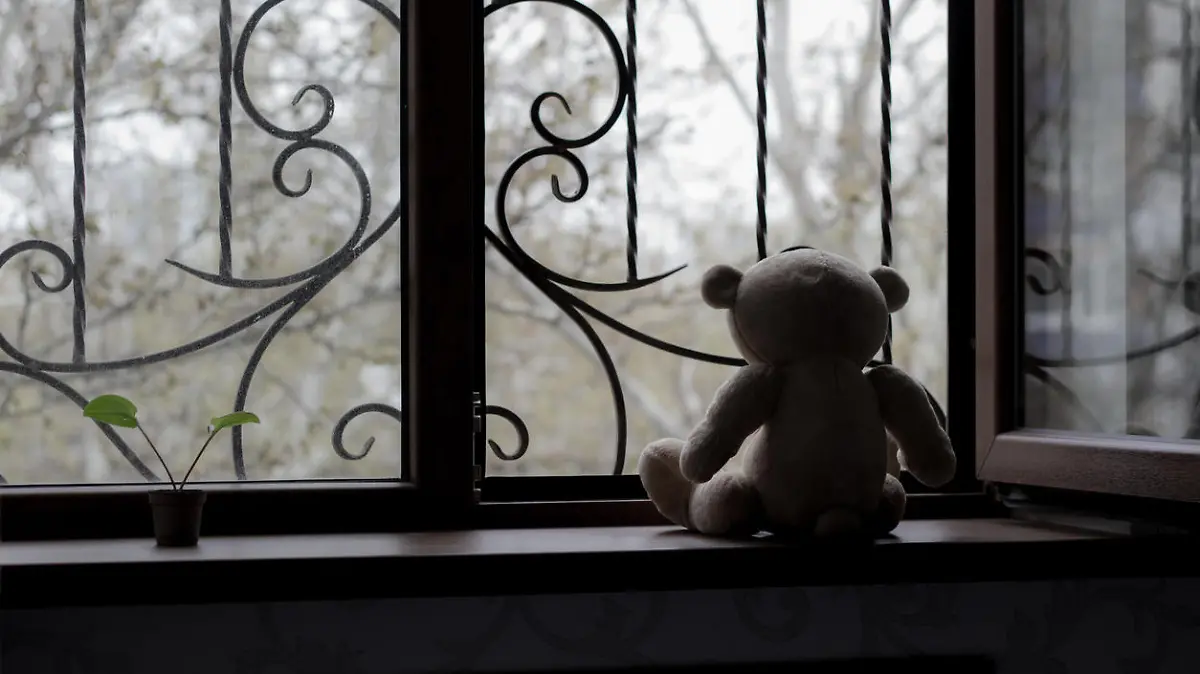 Teddybär schaut aus dem Fenster. Trauriges Bild.