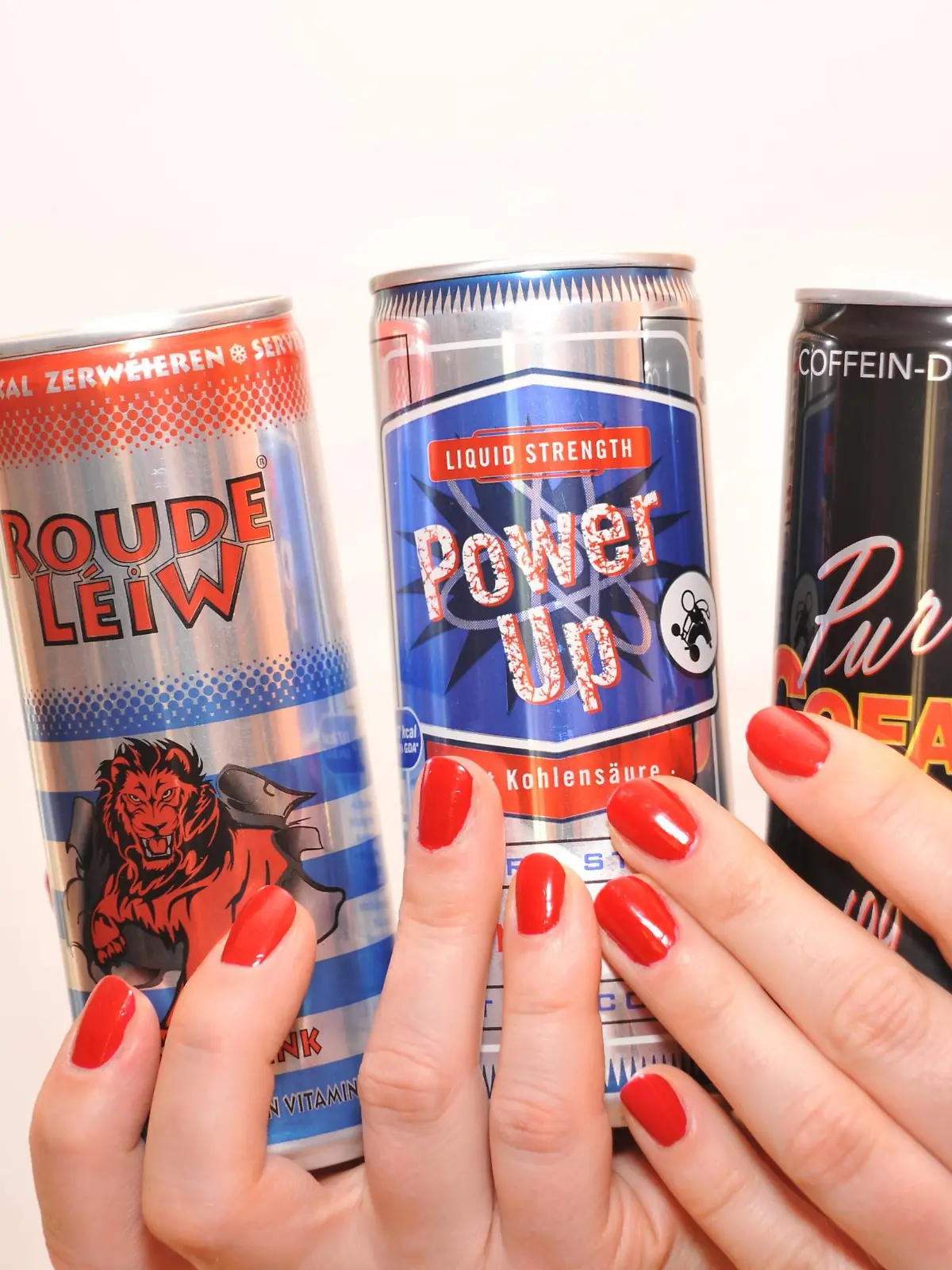Zwei Hände mit lackierten Fingernägeln halten mehrere Energy-Drinks