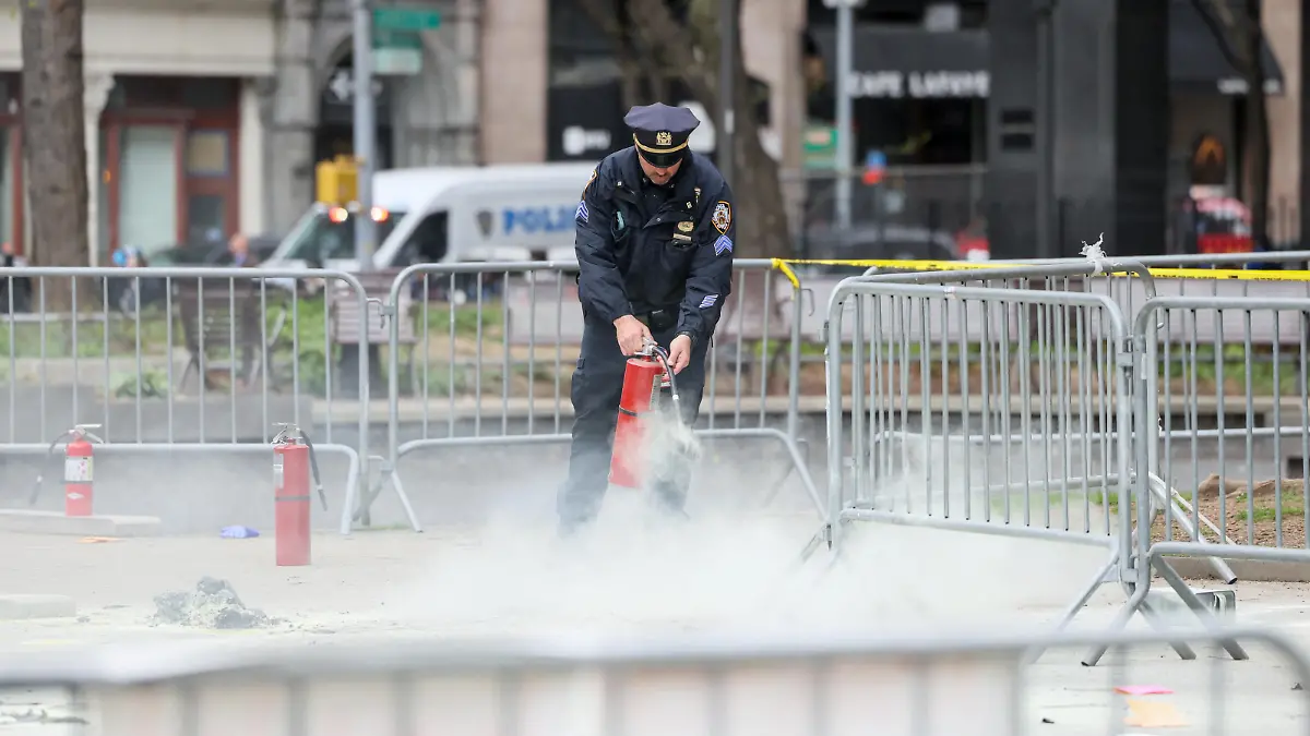 A police officer uses a fire extinguisher as emergency personnel respond to a report of a person covered in flames, outside the courthouse where former U.S. President Donald Trump's criminal hush money trial is underway, in New York, U.S., April 19, 2024. REUTERS/Brendan McDermid