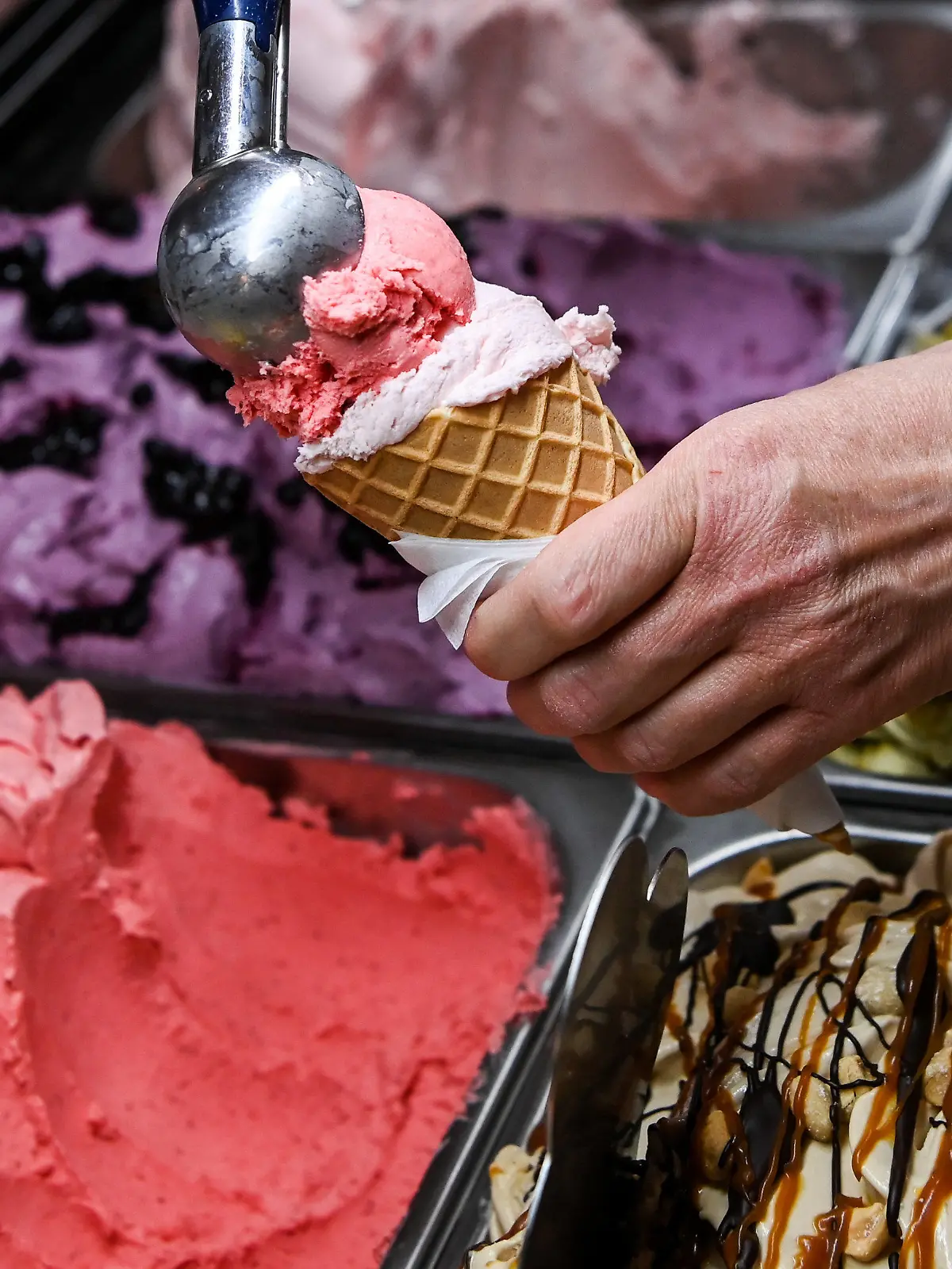 ARCHIV - 24.05.2022, Berlin: Eine Kugel Erdbeereis wird in einer Eisdiele auf eine weitere Kugel in einem Waffelhörnchen gesetzt. (zu dpa: ««Gelato Week Berlin» - Spezielle Eissorten zum Probieren») Foto: Jens Kalaene/dpa +++ dpa-Bildfunk +++