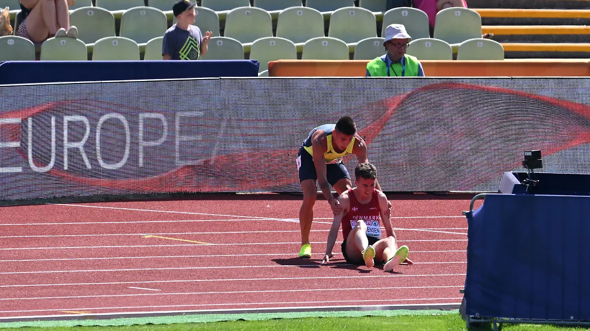 MUNICH, GERMANY - AUGUST 16: Nahuel Carabana of Andorra  stops to help injured Axel Vang Christensen of Denmark in the Men's 3000m Steeplechase Round 1 - Heat 1 during the Athletics competition on day 6 of the European Championships Munich 2022 at Olympiapark on August 16, 2022 in Munich, Germany. (Photo by Matthias Hangst/Getty Images)