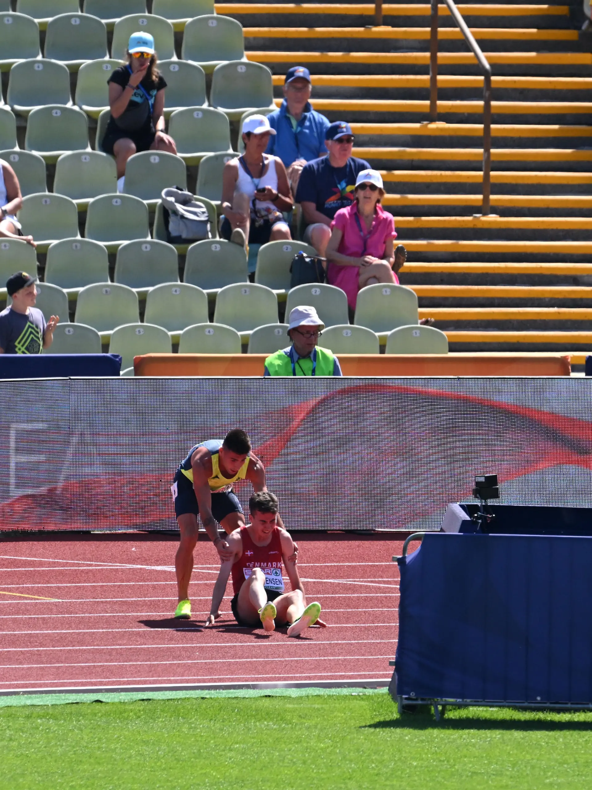 MUNICH, GERMANY - AUGUST 16: Nahuel Carabana of Andorra  stops to help injured Axel Vang Christensen of Denmark in the Men's 3000m Steeplechase Round 1 - Heat 1 during the Athletics competition on day 6 of the European Championships Munich 2022 at Olympiapark on August 16, 2022 in Munich, Germany. (Photo by Matthias Hangst/Getty Images)