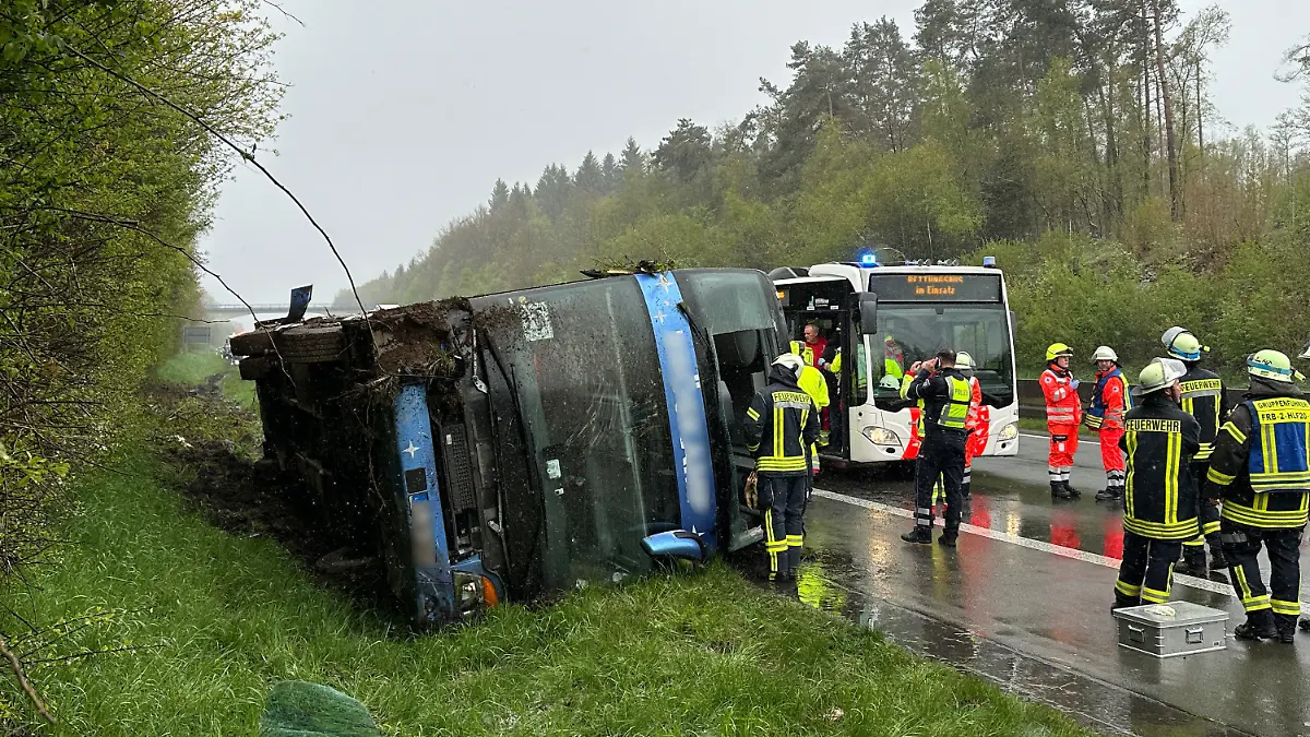 21.04.2024, Nordrhein-Westfalen, Olpe: Ein Bus liegt umgefallen am Straßenrand. Ein Reisebus mit Schülern ist am Sonntagmorgen auf der Autobahn 45 im Sauerland umgestürzt. Acht Jugendliche wurden nach Angaben der Polizei von Sonntag leicht verletzt und von Rettungskräften versorgt. Die Schüler und ihre Lehrer waren demnach am frühen Morgen aus Marburg in Hessen mit dem Ziel England aufgebrochen. Bei dem Ort Wenden sei der Bus aus noch ungeklärter Ursache von der Fahrbahn abgekommen und auf die Seite gekippt, wo er liegenblieb. Foto: Berthold Stamm/dpa +++ dpa-Bildfunk +++
