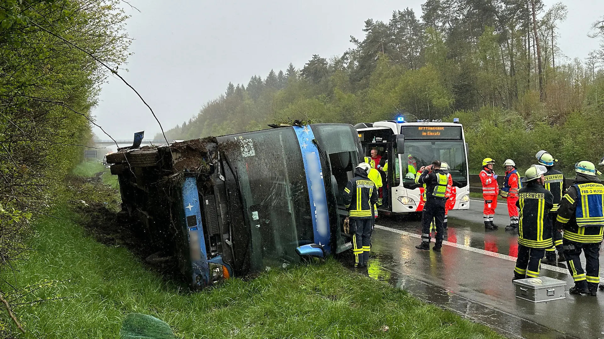 21.04.2024, Nordrhein-Westfalen, Olpe: Ein Bus liegt umgefallen am Straßenrand. Ein Reisebus mit Schülern ist am Sonntagmorgen auf der Autobahn 45 im Sauerland umgestürzt. Acht Jugendliche wurden nach Angaben der Polizei von Sonntag leicht verletzt und von Rettungskräften versorgt. Die Schüler und ihre Lehrer waren demnach am frühen Morgen aus Marburg in Hessen mit dem Ziel England aufgebrochen. Bei dem Ort Wenden sei der Bus aus noch ungeklärter Ursache von der Fahrbahn abgekommen und auf die Seite gekippt, wo er liegenblieb. Foto: Berthold Stamm/dpa +++ dpa-Bildfunk +++