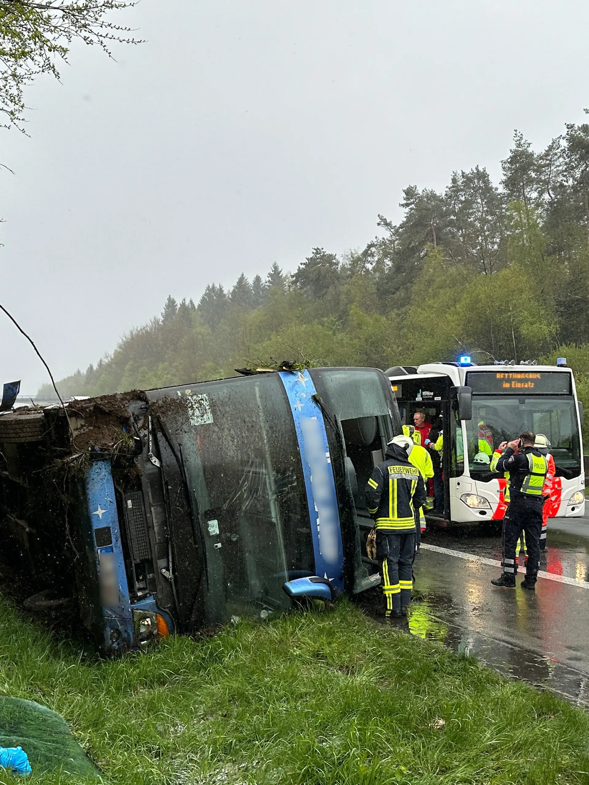 21.04.2024, Nordrhein-Westfalen, Olpe: Ein Bus liegt umgefallen am Straßenrand. Ein Reisebus mit Schülern ist am Sonntagmorgen auf der Autobahn 45 im Sauerland umgestürzt. Acht Jugendliche wurden nach Angaben der Polizei von Sonntag leicht verletzt und von Rettungskräften versorgt. Die Schüler und ihre Lehrer waren demnach am frühen Morgen aus Marburg in Hessen mit dem Ziel England aufgebrochen. Bei dem Ort Wenden sei der Bus aus noch ungeklärter Ursache von der Fahrbahn abgekommen und auf die Seite gekippt, wo er liegenblieb. Foto: Berthold Stamm/dpa +++ dpa-Bildfunk +++