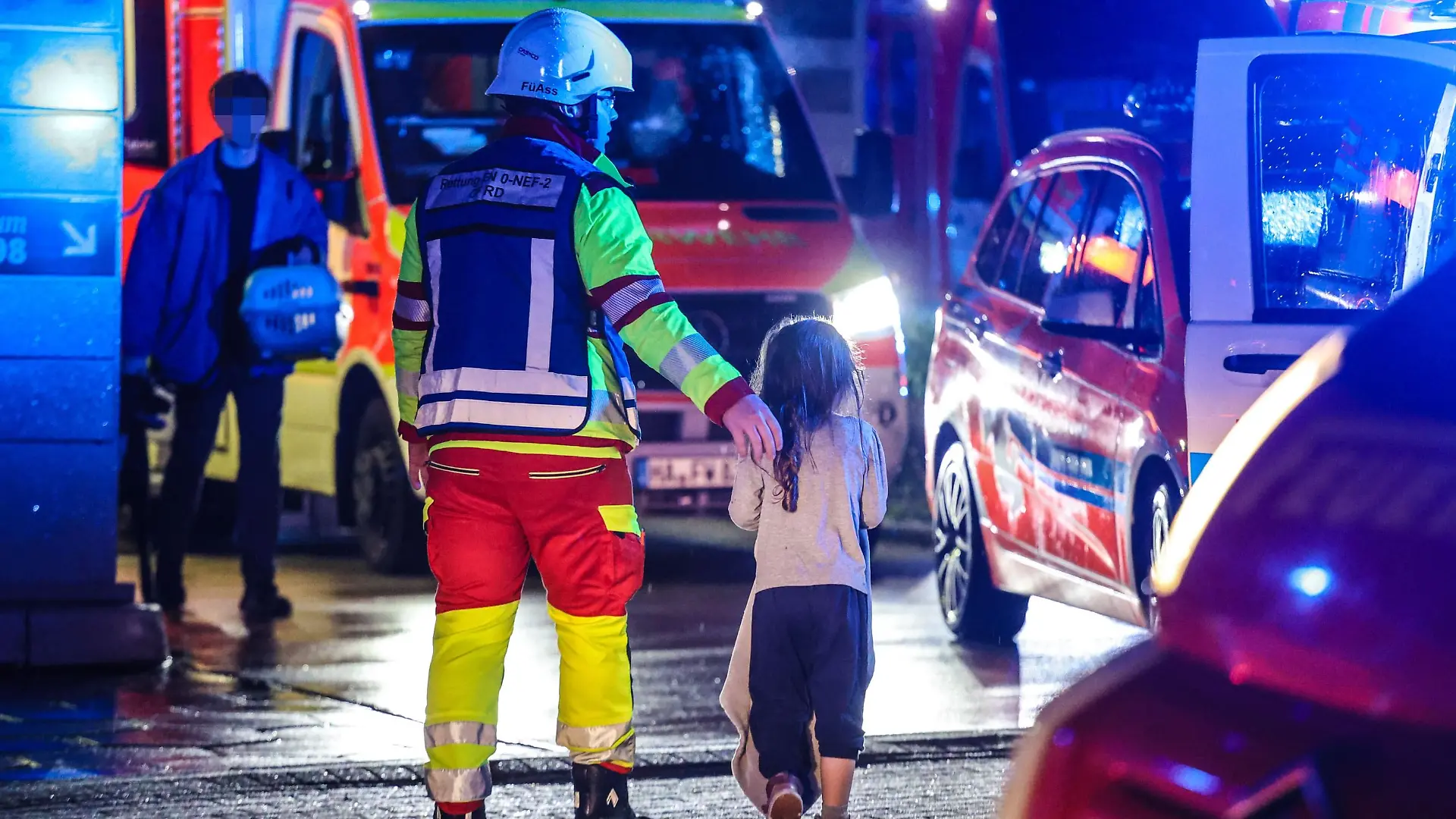 Der Feuerwehrmann berührt das Mädchen beschützend an der Schulter. Das Zuhause des Kindes ist nach dem Brand unbewohnbar.