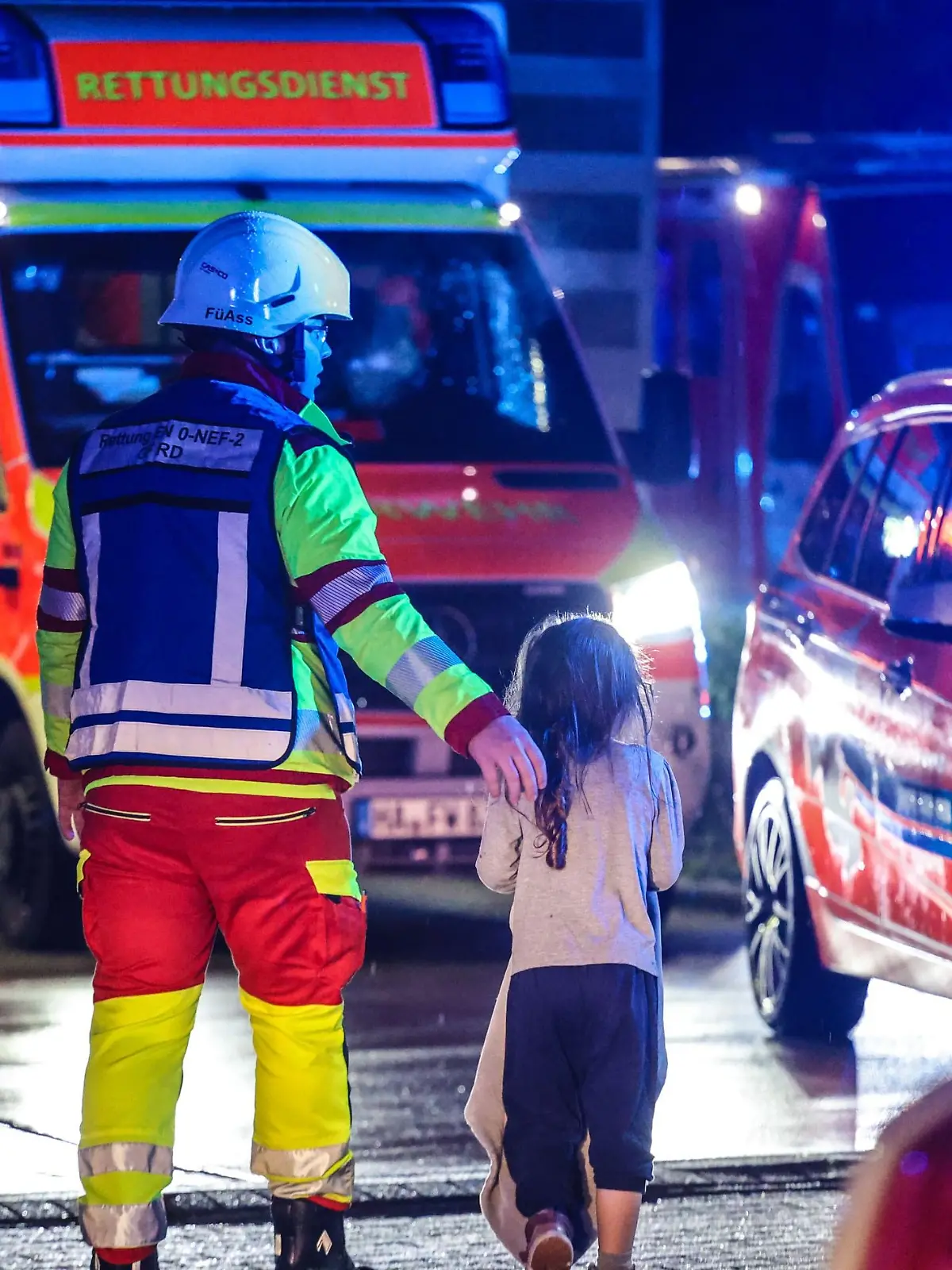 Der Feuerwehrmann berührt das Mädchen beschützend an der Schulter. Das Zuhause des Kindes ist nach dem Brand unbewohnbar.